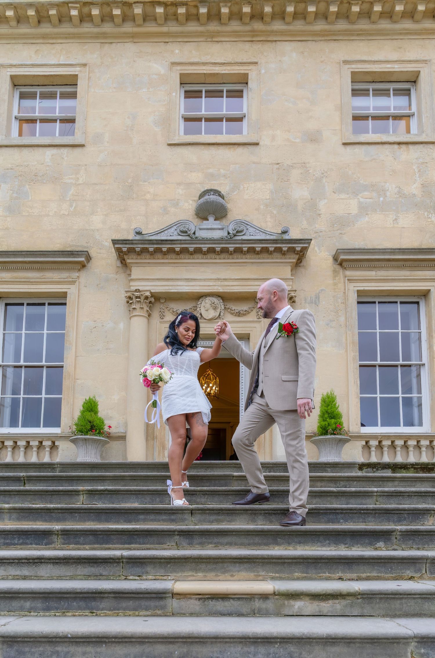 Couple poses on stone steps of historic building exterior during wedding photoshoot.
