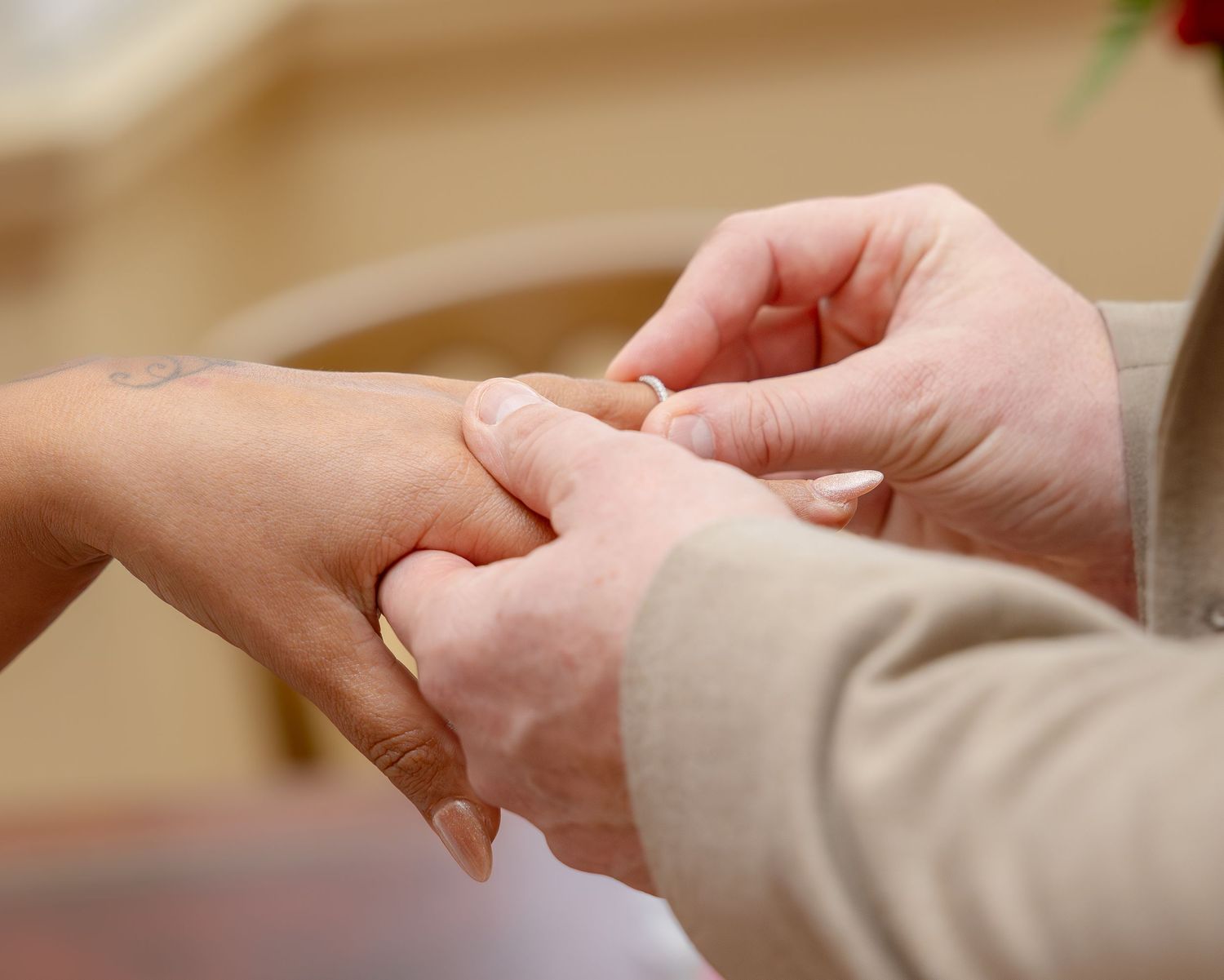 Groom placing wedding ring on brides finger during intimate ring exchange ceremony close-up.