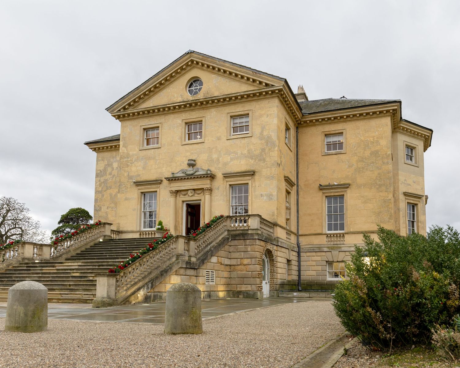 Side angle view of an elegant Georgian country house with stone facade and manicured grounds.