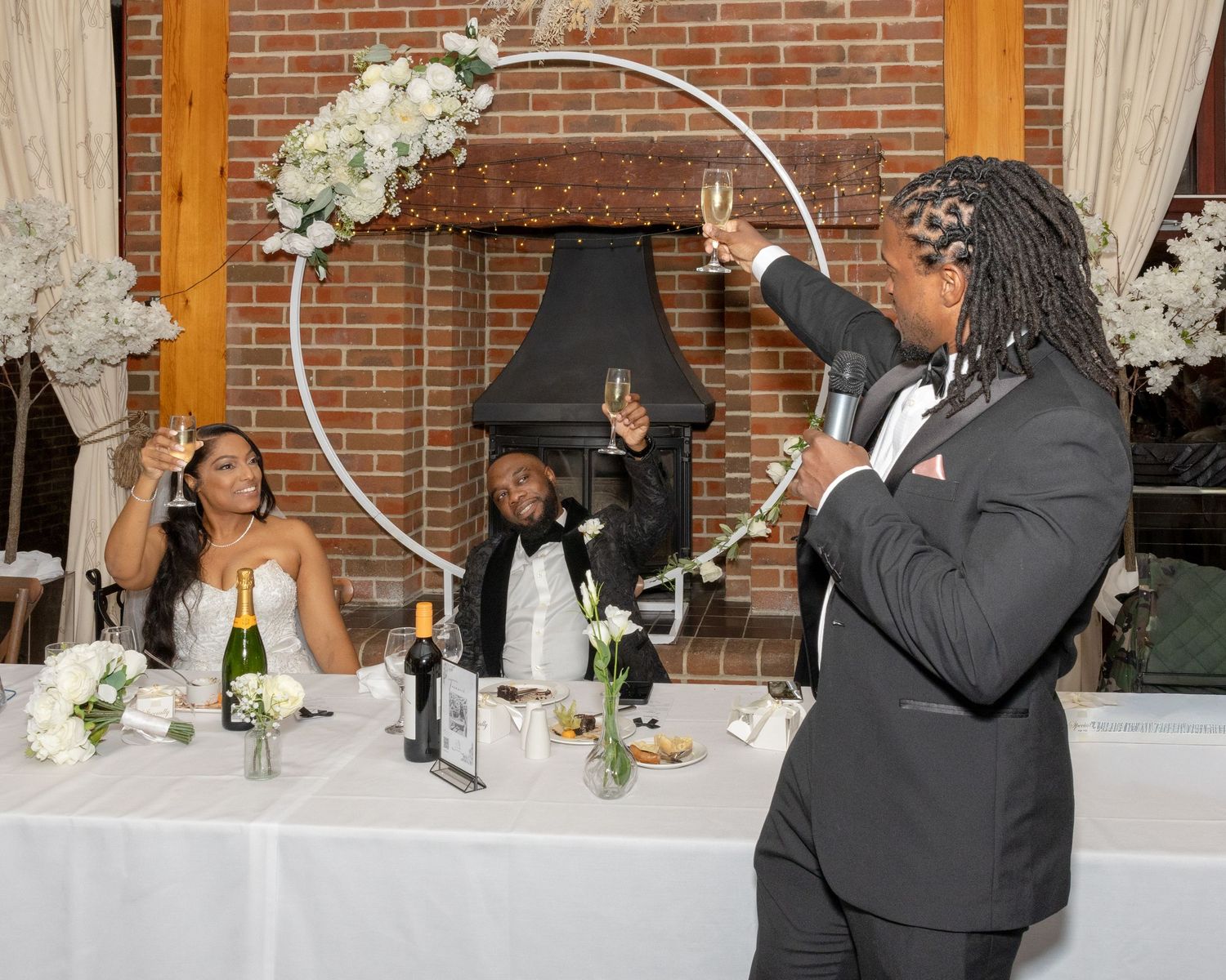 Best man raises a champagne toast to the bride and groom at the wedding reception head table.
