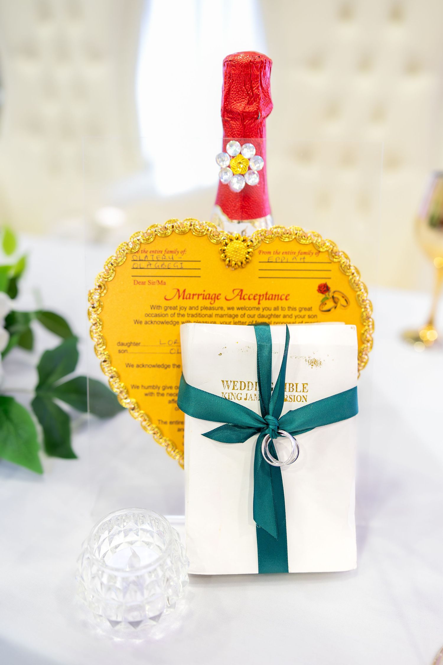 Nigerian traditional wedding bible, marriage acceptance card, and champagne bottle on decorated table.