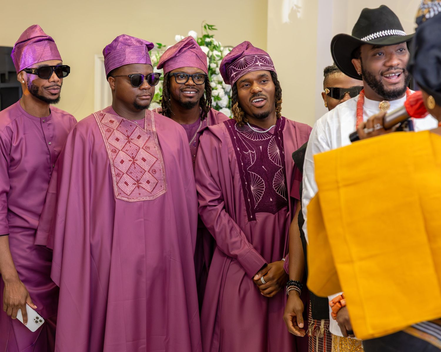 Groomsmen in matching purple agbada traditional attire pose together at a Nigerian traditional wedding ceremony.