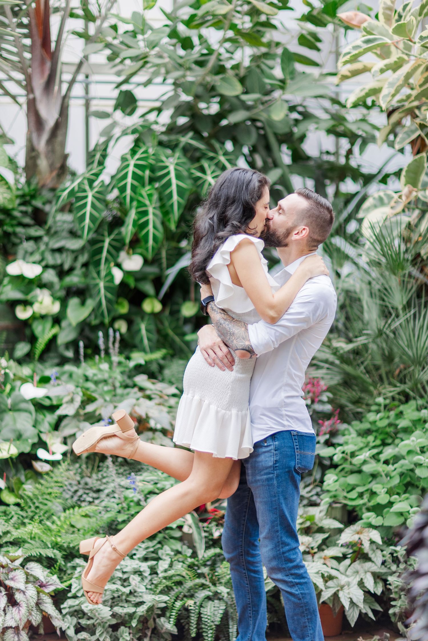 A romantic dance sequence captured in a greenhouse filled with lush tropical plants.
