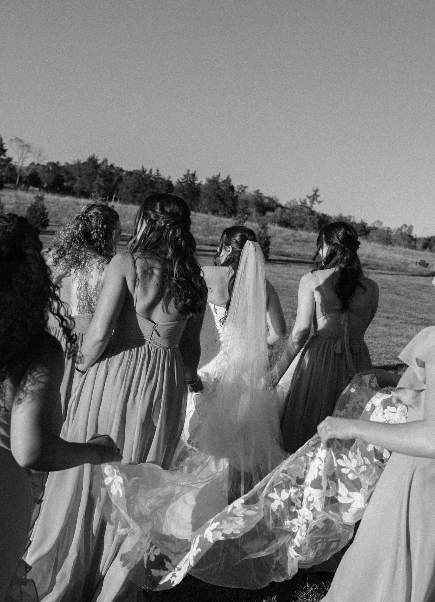 Wedding party in black and white showing bridesmaids in flowing dresses standing together outdoors.