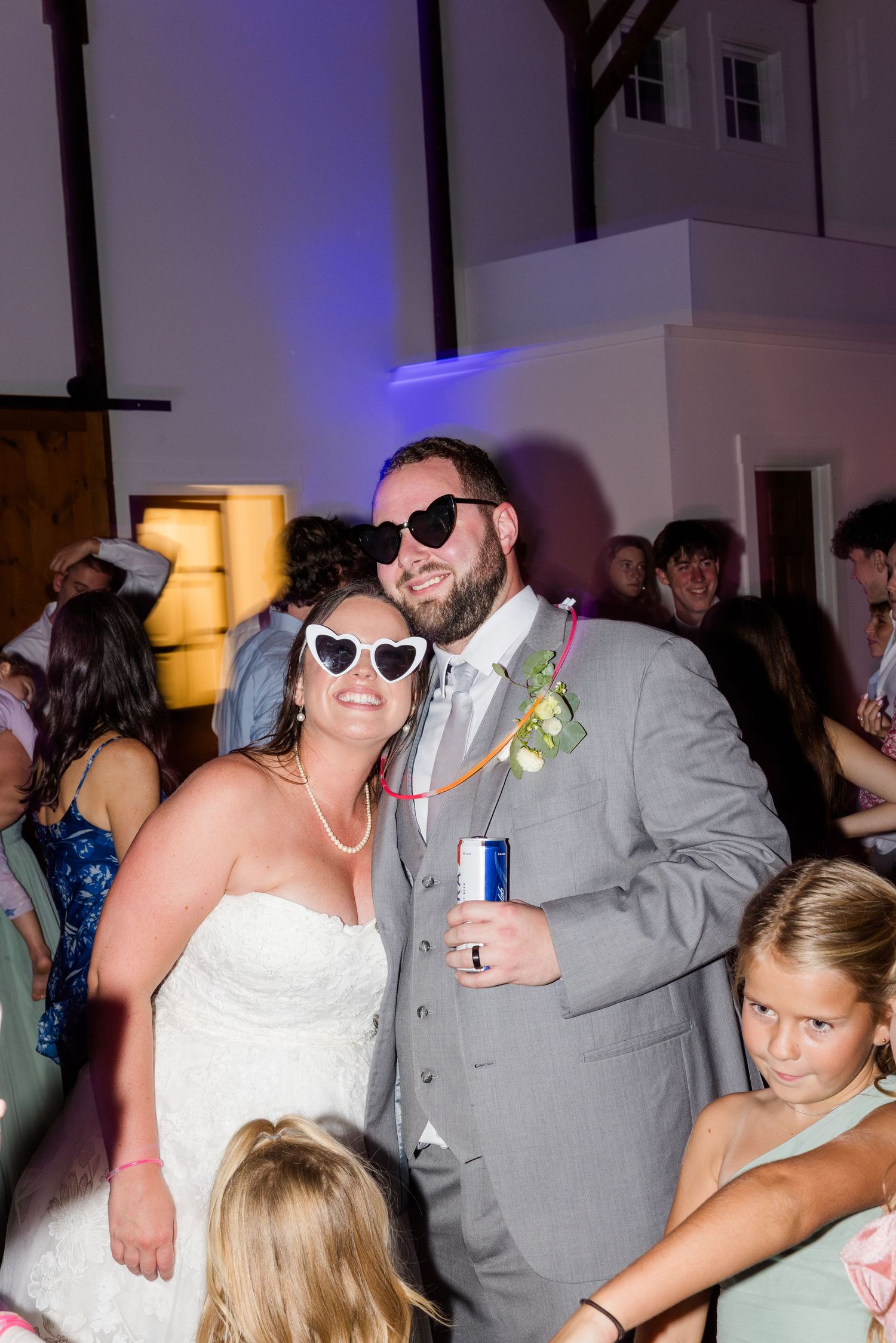 Wedding celebration on dance floor with guests wearing sunglasses and having fun.