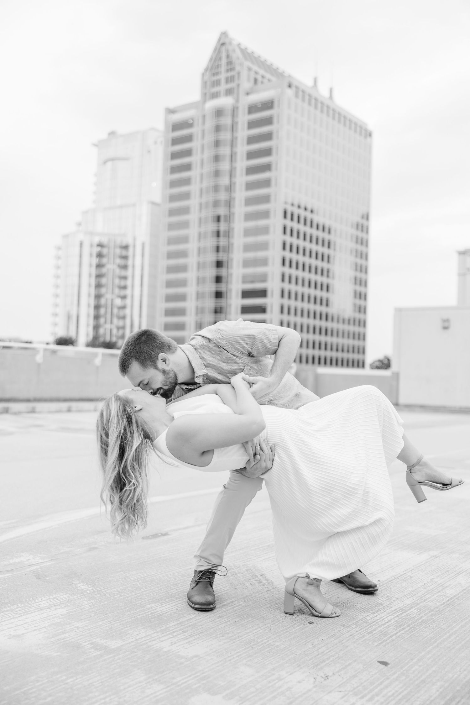 A romantic black and white photo sequence showing a couple dancing and dipping in front of city buildings.