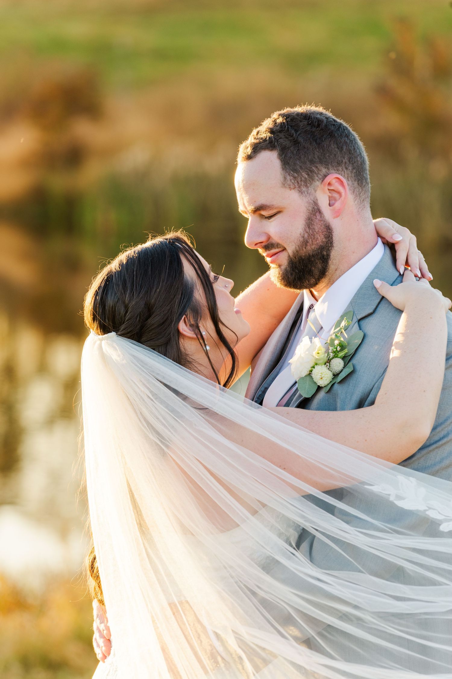 Flowing wedding veil catches sunlight during outdoor portrait session.