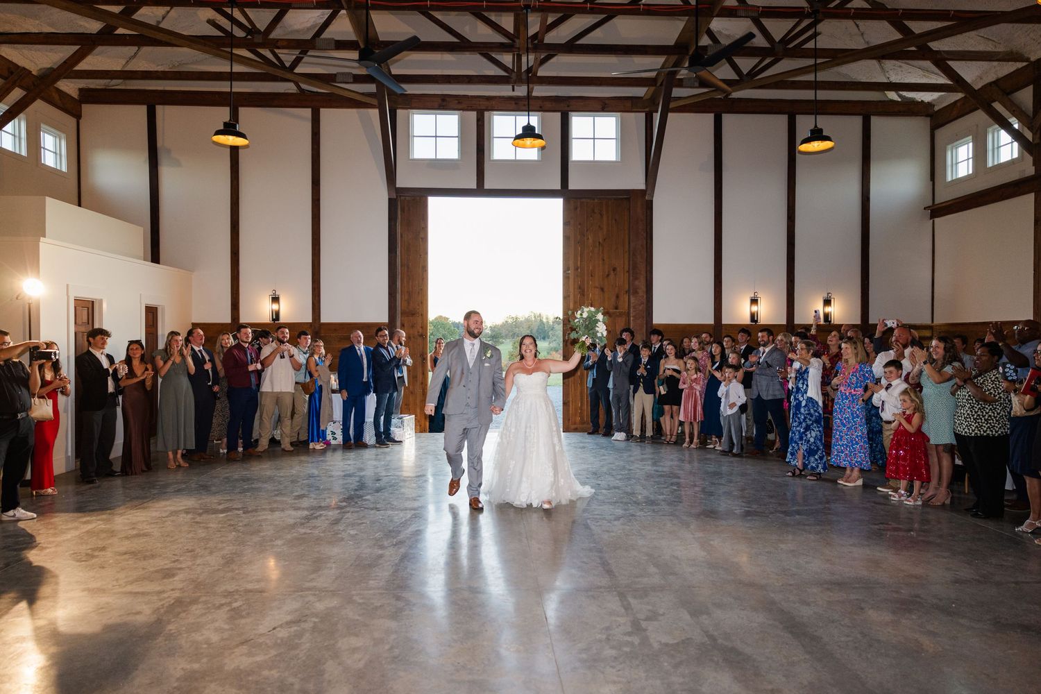 Panoramic view of rustic wedding reception venue with exposed wooden beams.