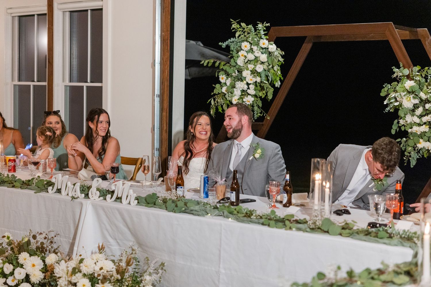 Elegant wedding reception table setup with white floral centerpieces and greenery.