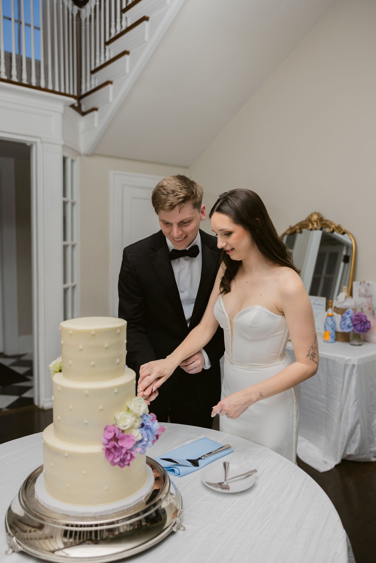 Newlyweds cut their elegant white wedding cake together at the reception.