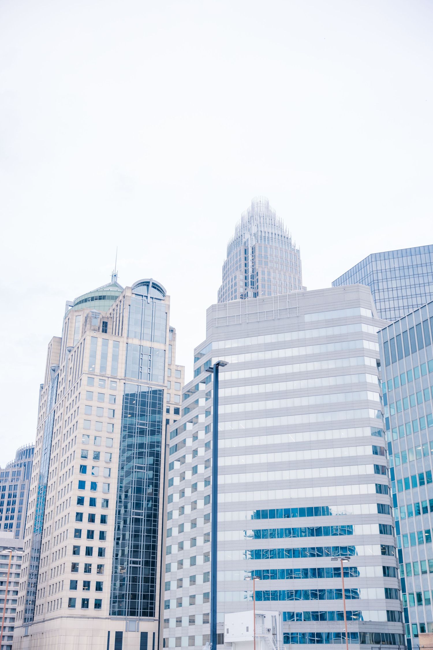 Modern office buildings and skyscrapers create a geometric cityscape against a bright white sky.
