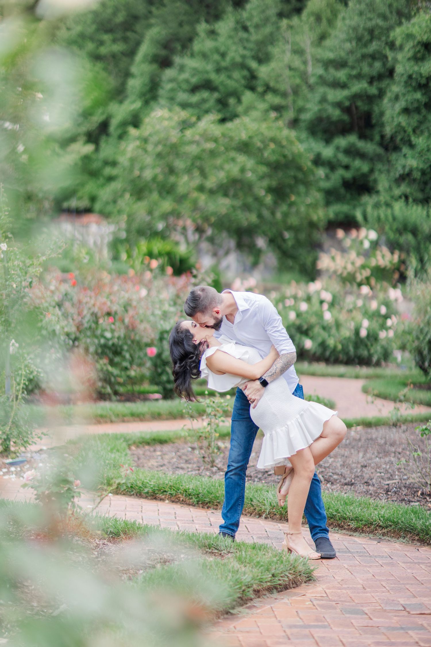 A romantic dip pose sequence captured on brick pathways surrounded by blooming garden flowers.