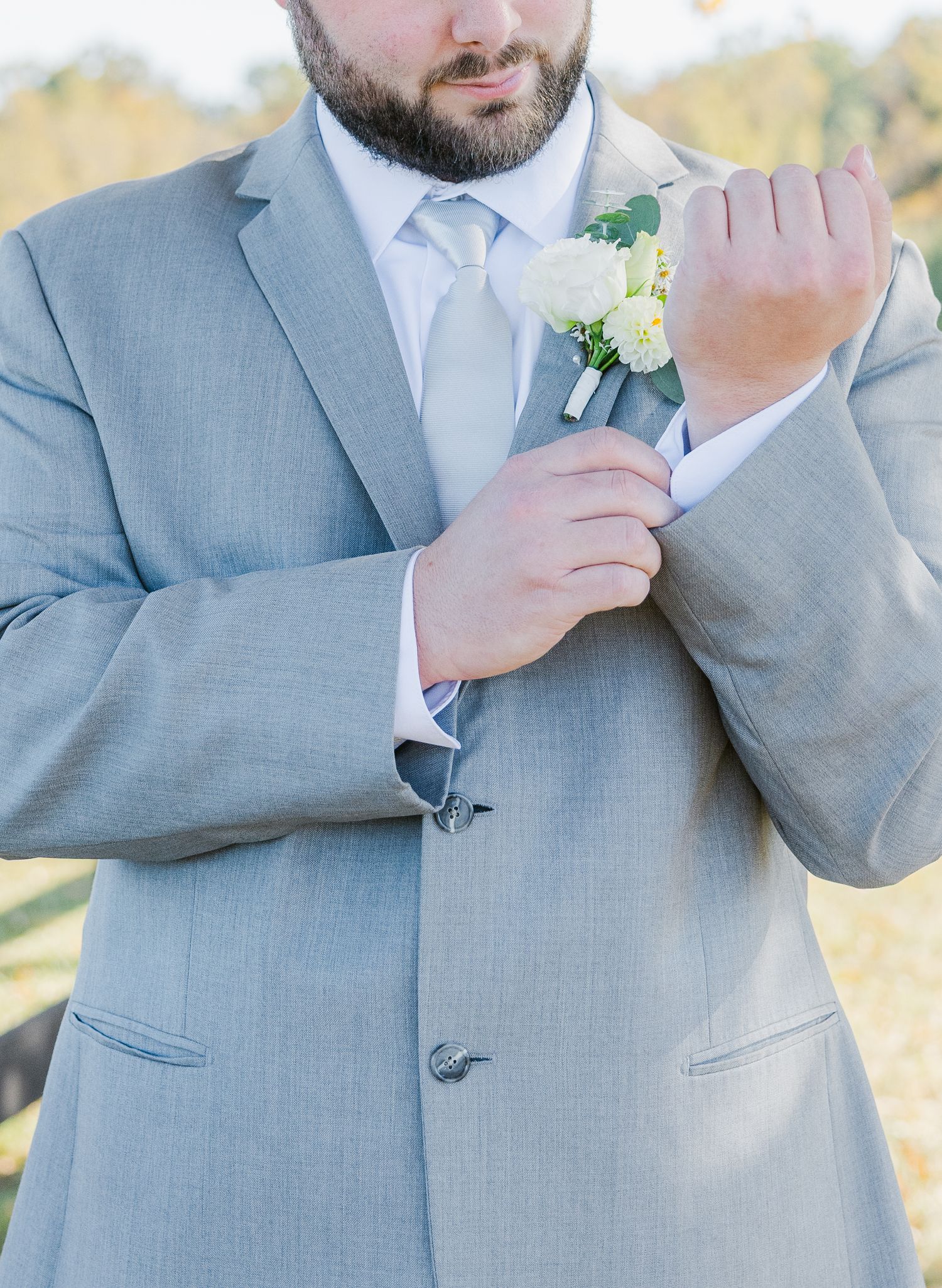 Groomsmen in light gray suits with boutonnieres pose for detail shots.