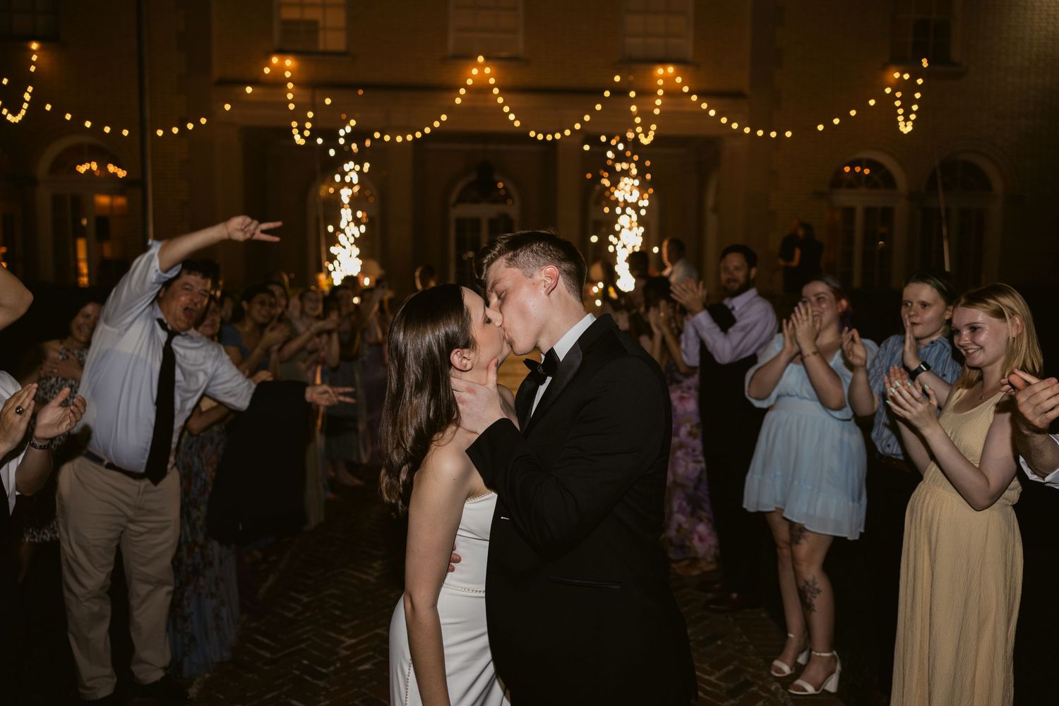 Wedding reception dance floor filled with guests under warm string lights.