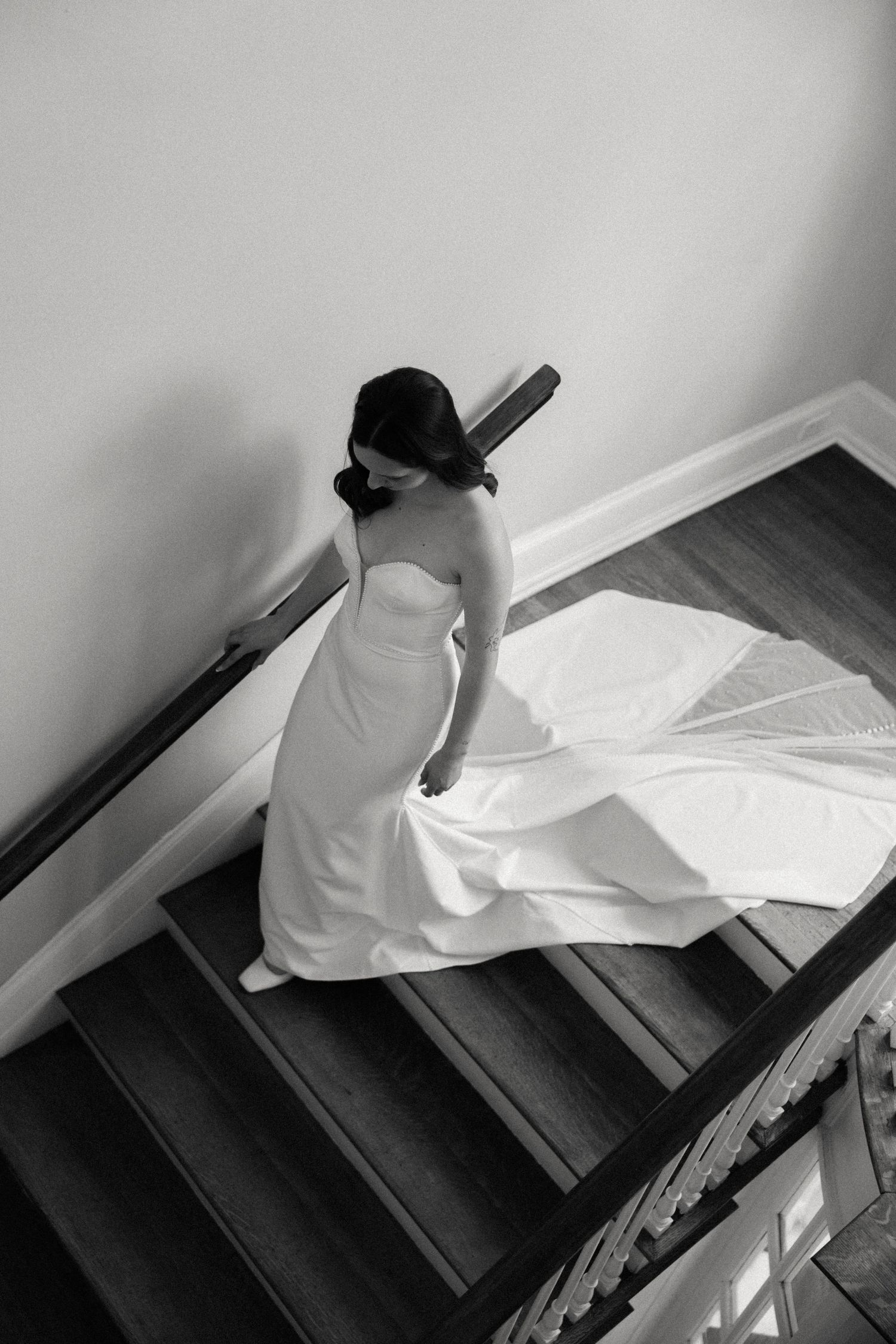 Black and white image of descending wooden stairs with white fabric trailing down.