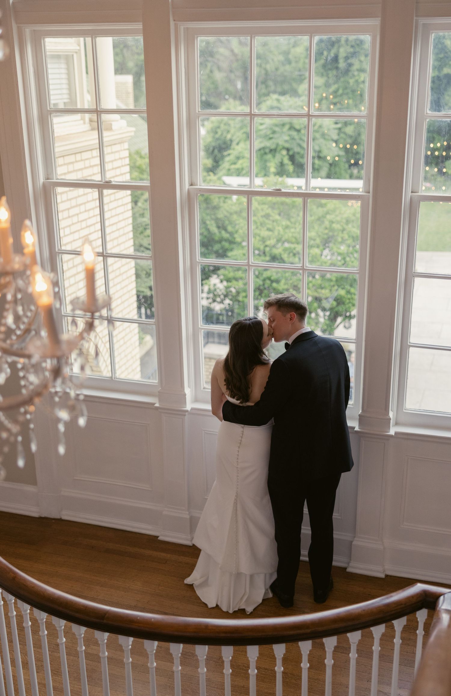 Dancing silhouettes against bright windows in an elegant room with chandelier.