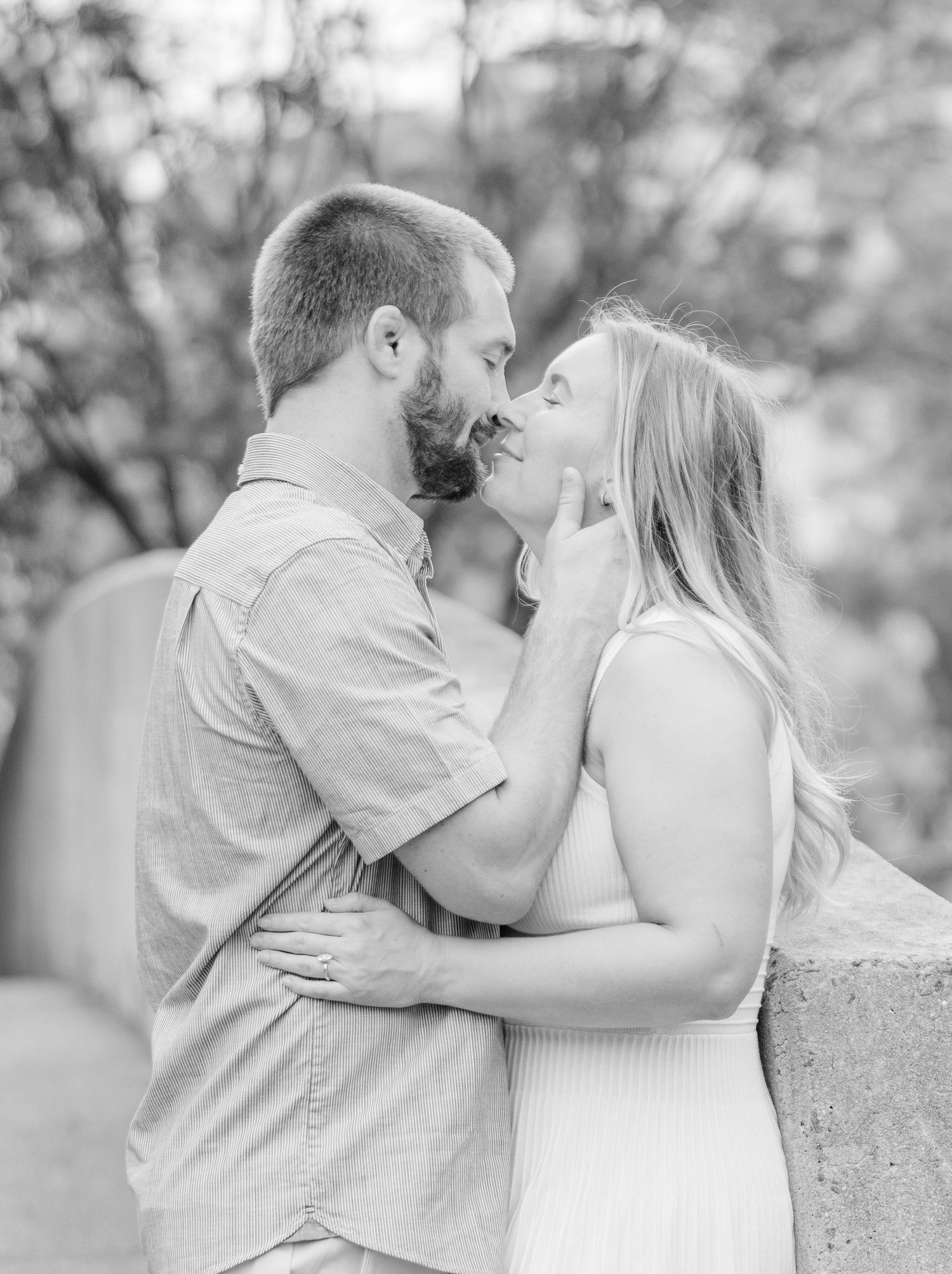 A romantic black and white photo sequence shows a couple embracing and sharing tender moments on a stone wall outdoors.
