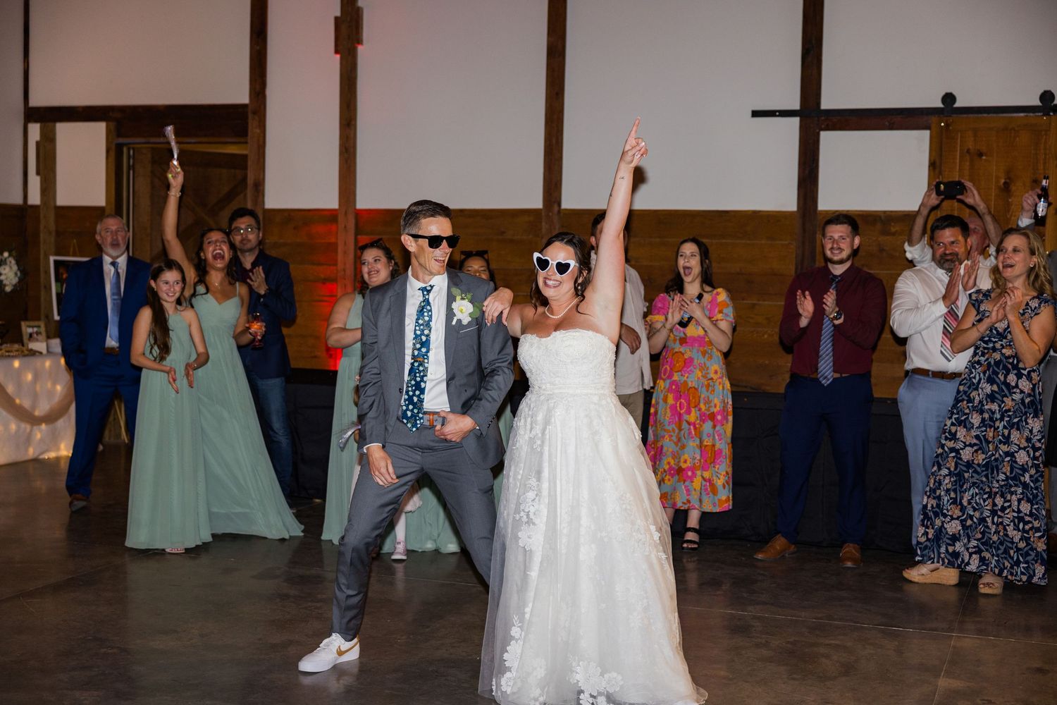 Wedding guests dancing and celebrating on a dimly lit reception dance floor.