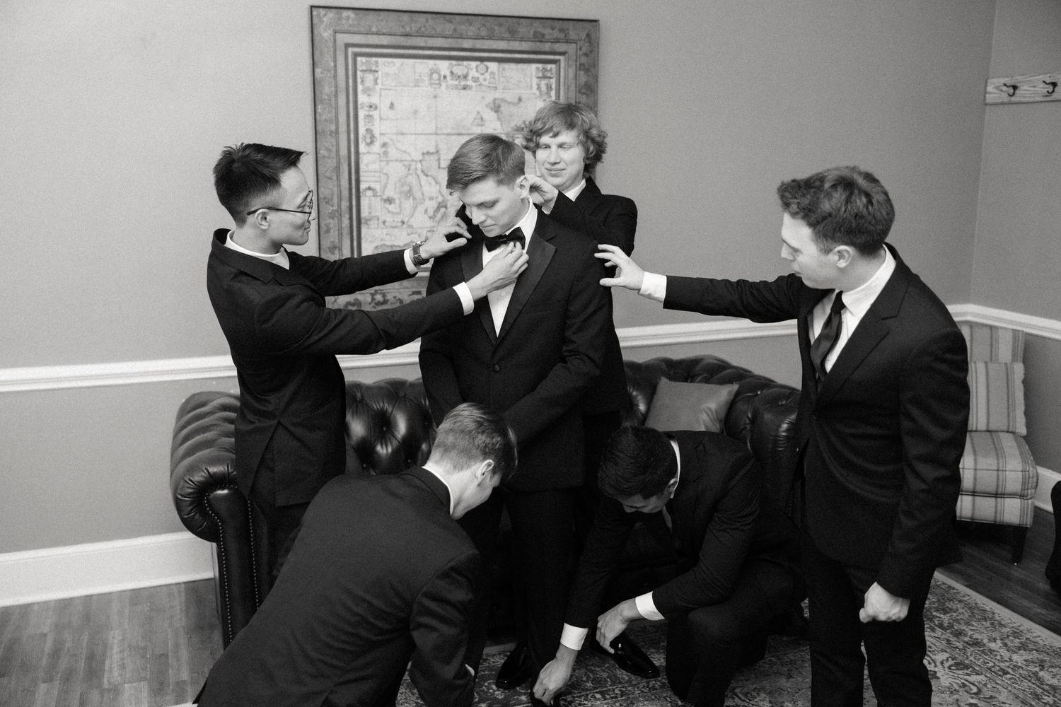 A sequence of black and white photographs showing people in suits engaged in a playful scuffle or mock fight.