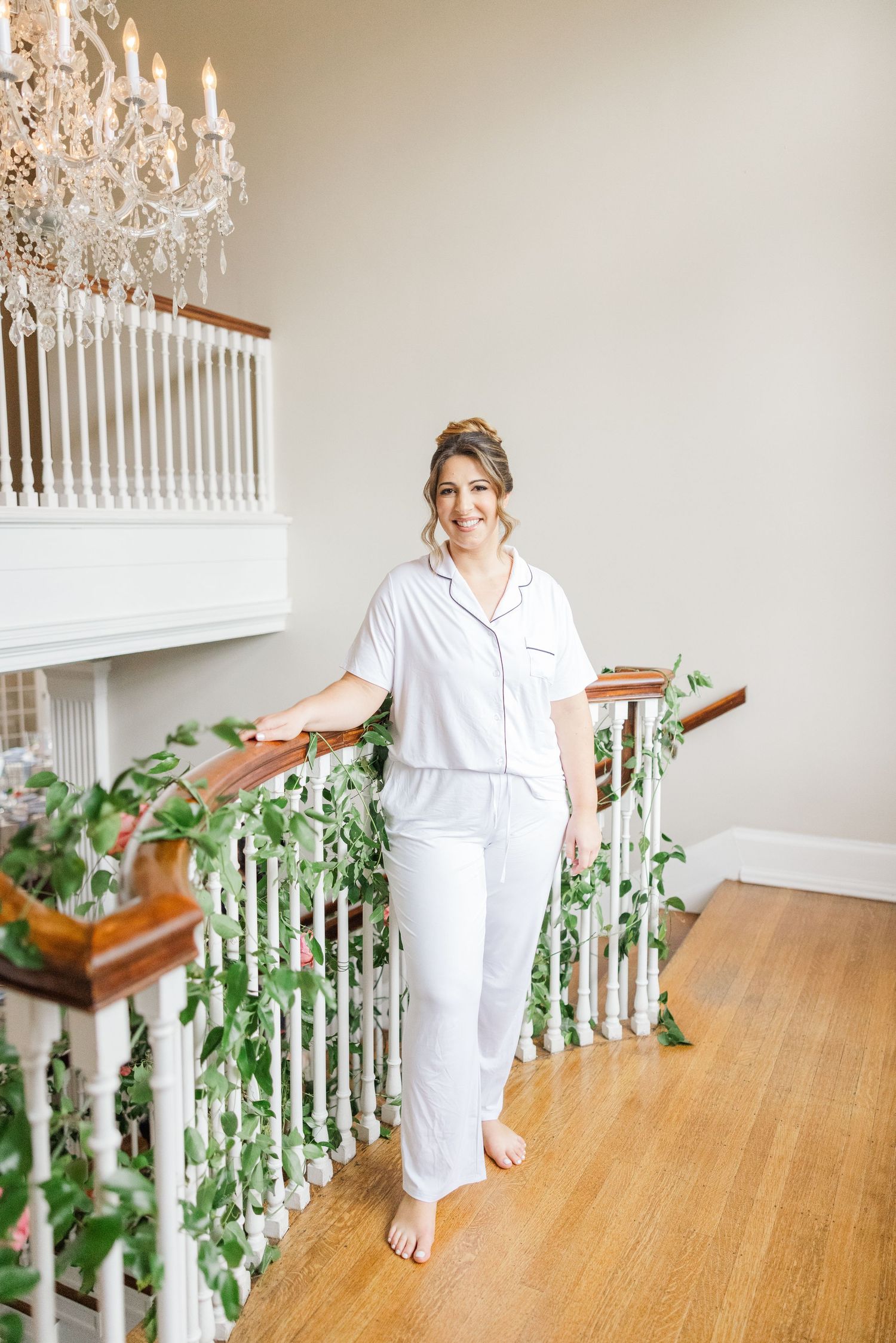 White-clad figure descends elegant staircase decorated with greenery and floral accents.