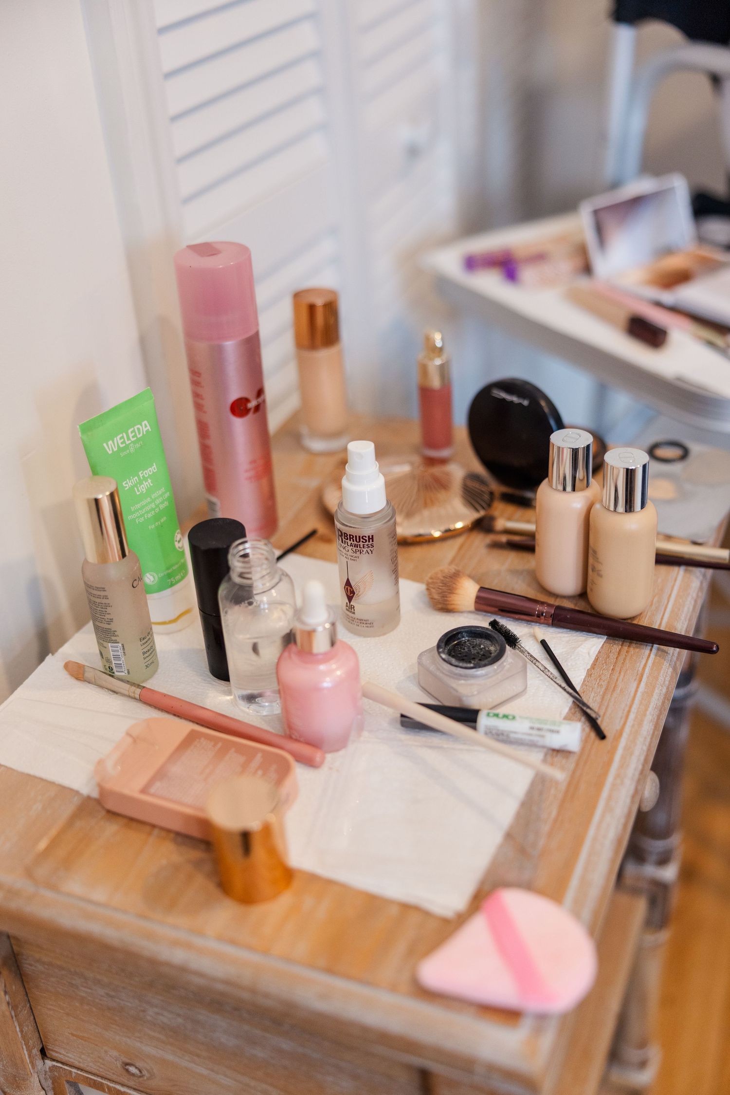 Wedding day makeup and beauty products arranged on wooden vanity table with soft natural lighting.