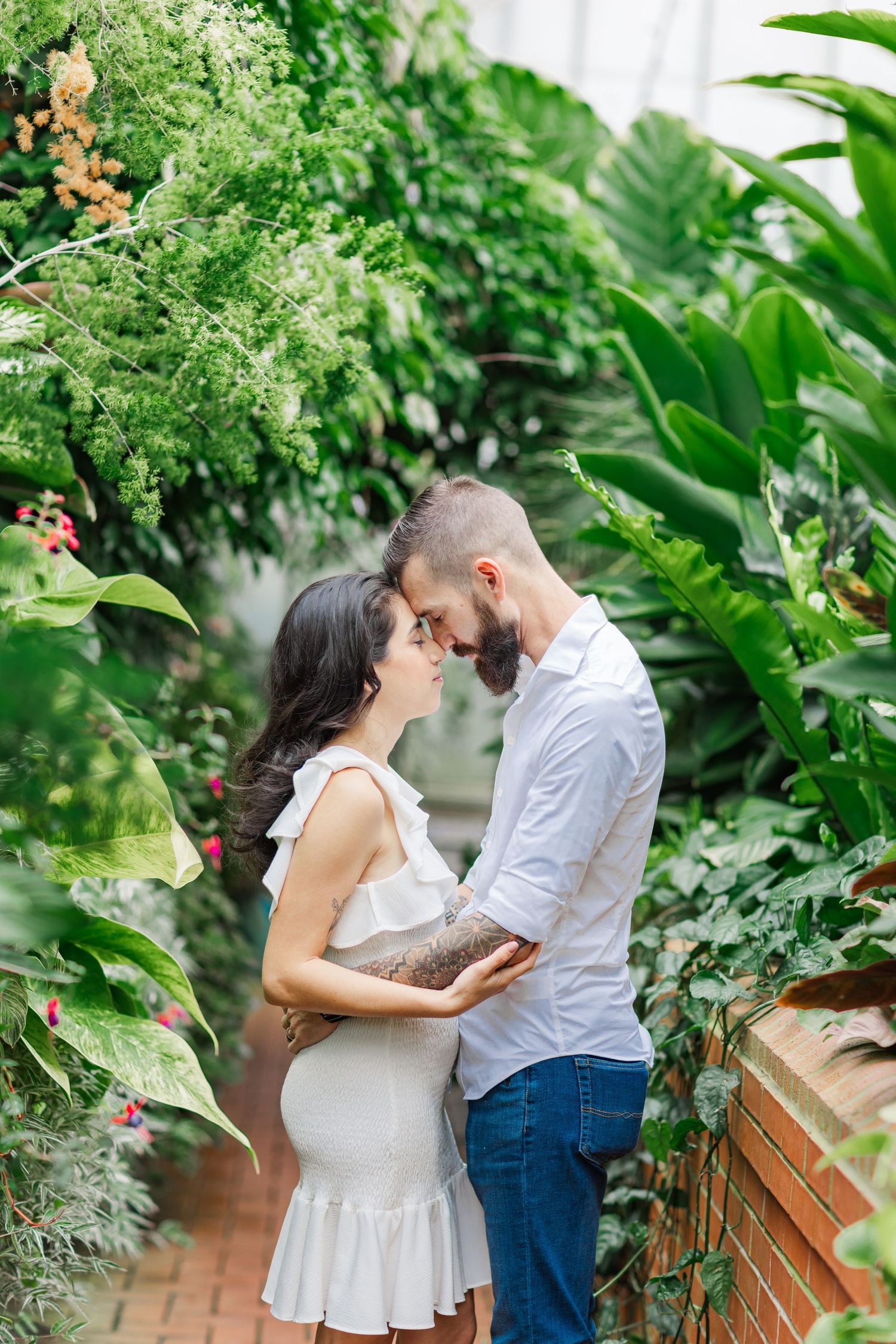 Intimate moment shared in greenhouse setting with brick pathway and tropical foliage.