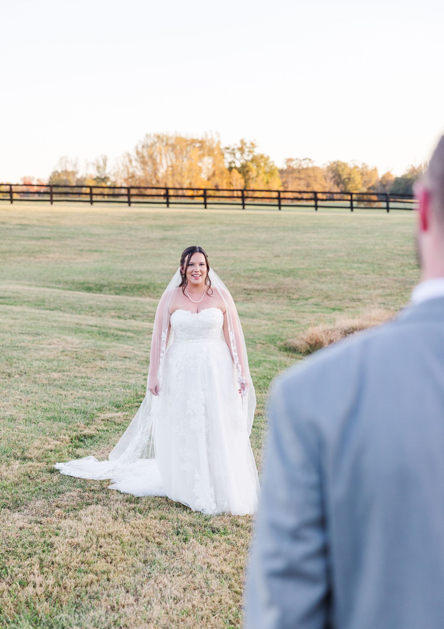 A bride and groom share their first look moment in a scenic outdoor field setting.