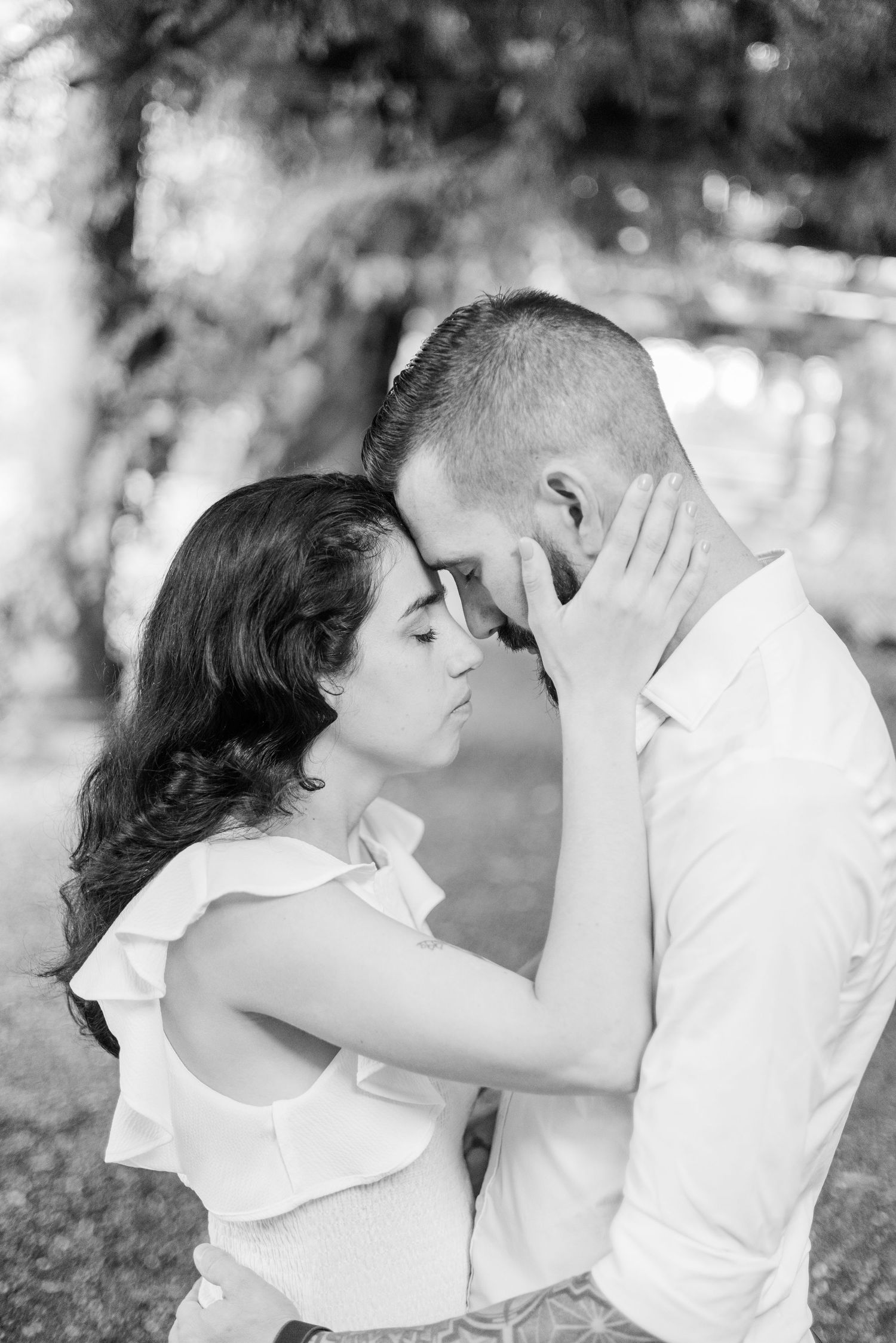 A tender black and white portrait of a couple sharing an intimate moment in a garden setting.