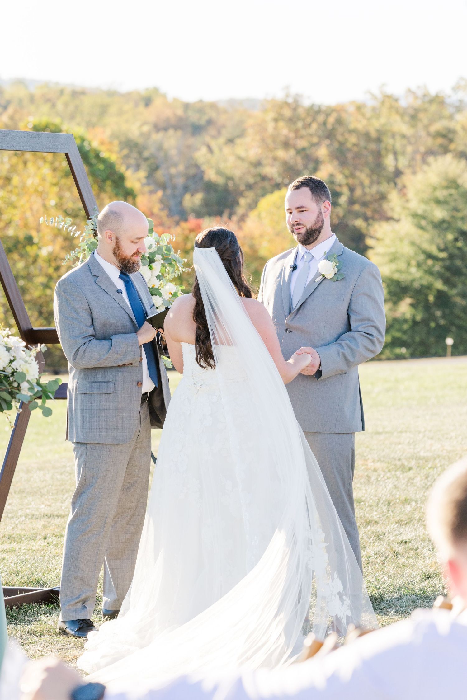 Wedding ceremony moments captured in bright natural lighting with grey suited groomsmen.