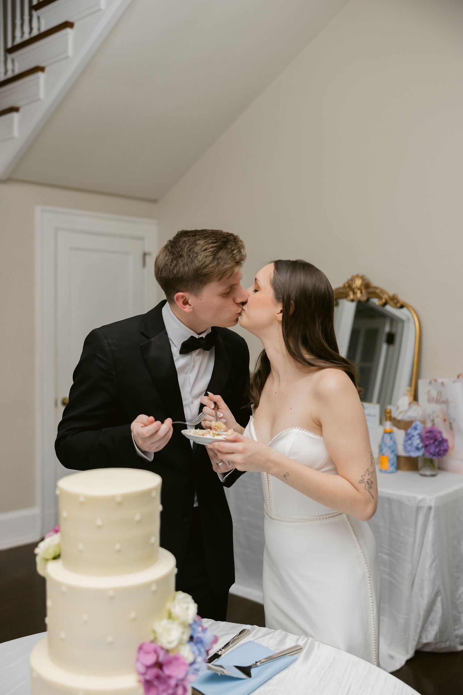 A traditional wedding cake-cutting moment in an elegant white reception room.