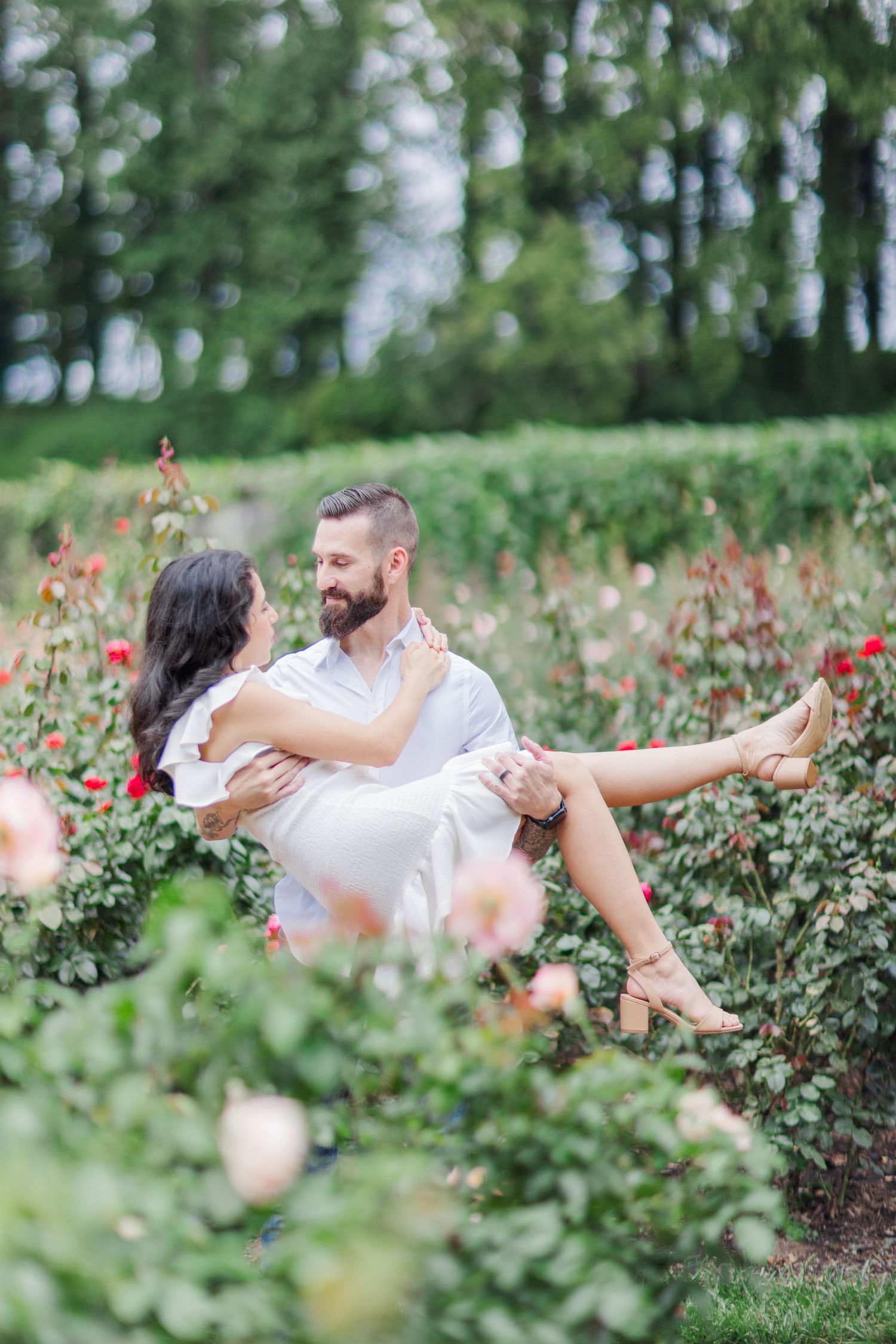 Couple shares intimate dance moves in a blooming rose garden on a sunny afternoon.