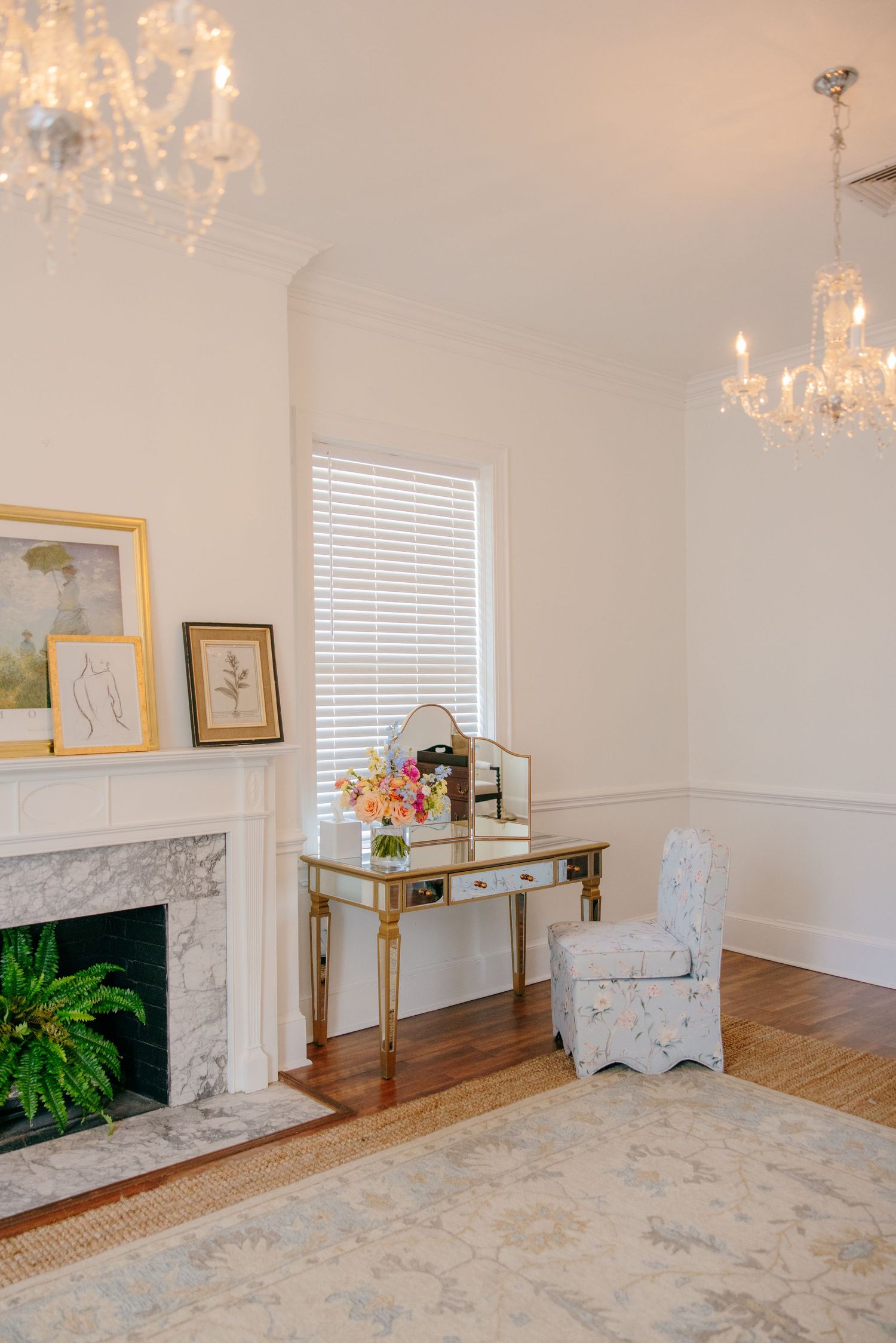 Elegant living room interior with crystal chandelier, marble fireplace, and mirrored console table.