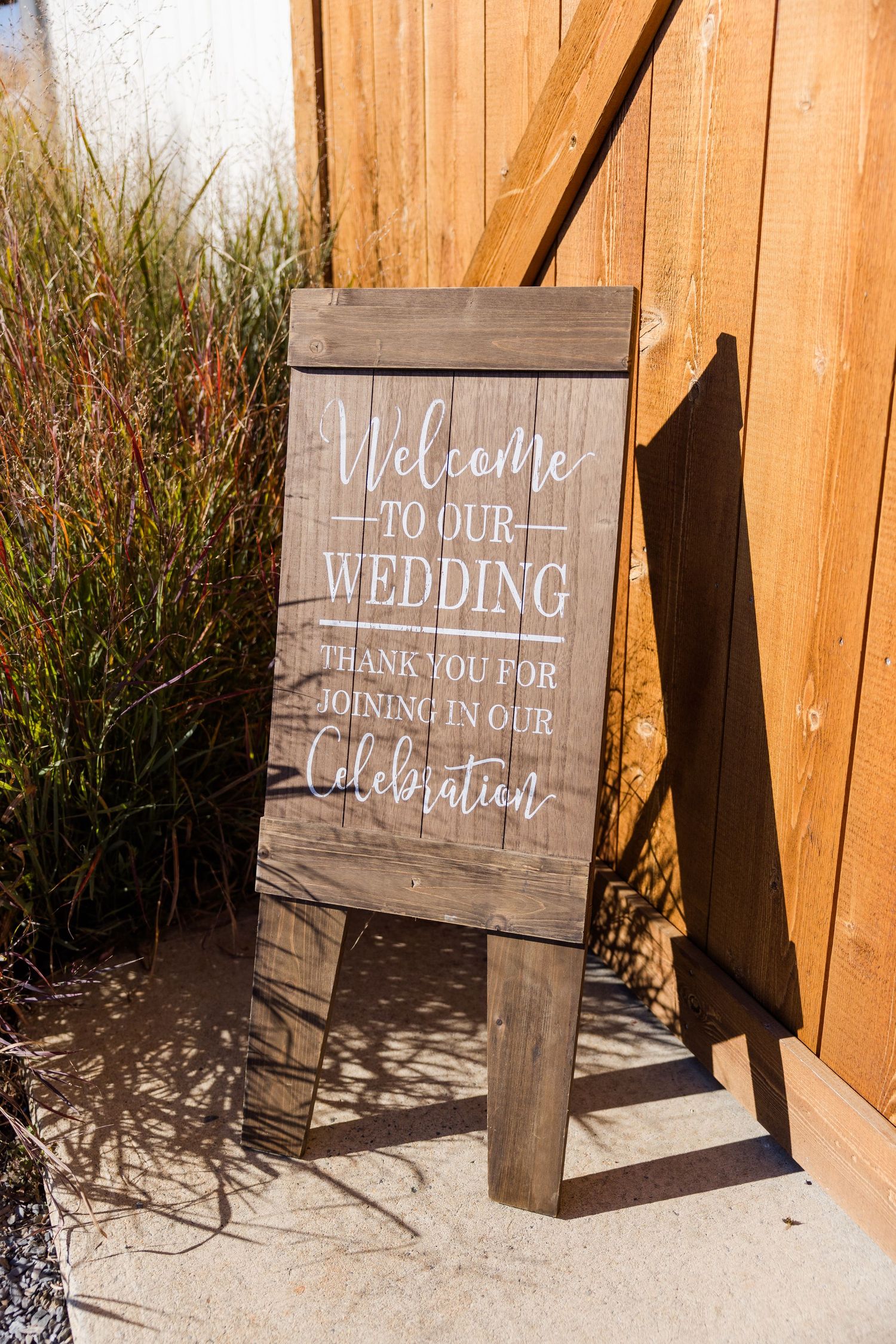 Rustic wooden wedding signs with welcome messages displayed against barn door background.