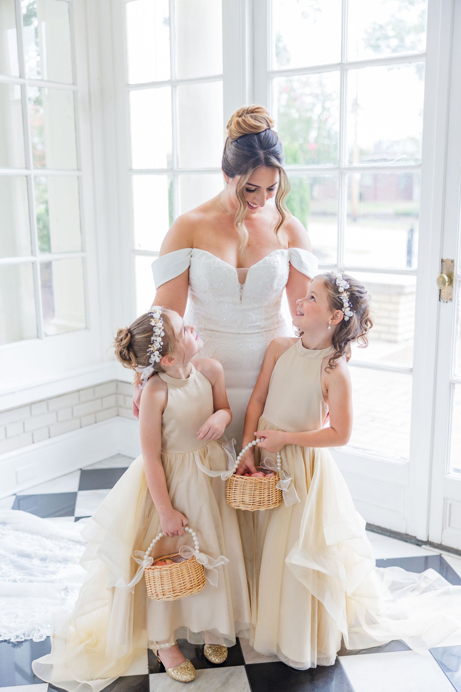 Wedding party in cream dresses sharing intimate moment in bright sunlit room.