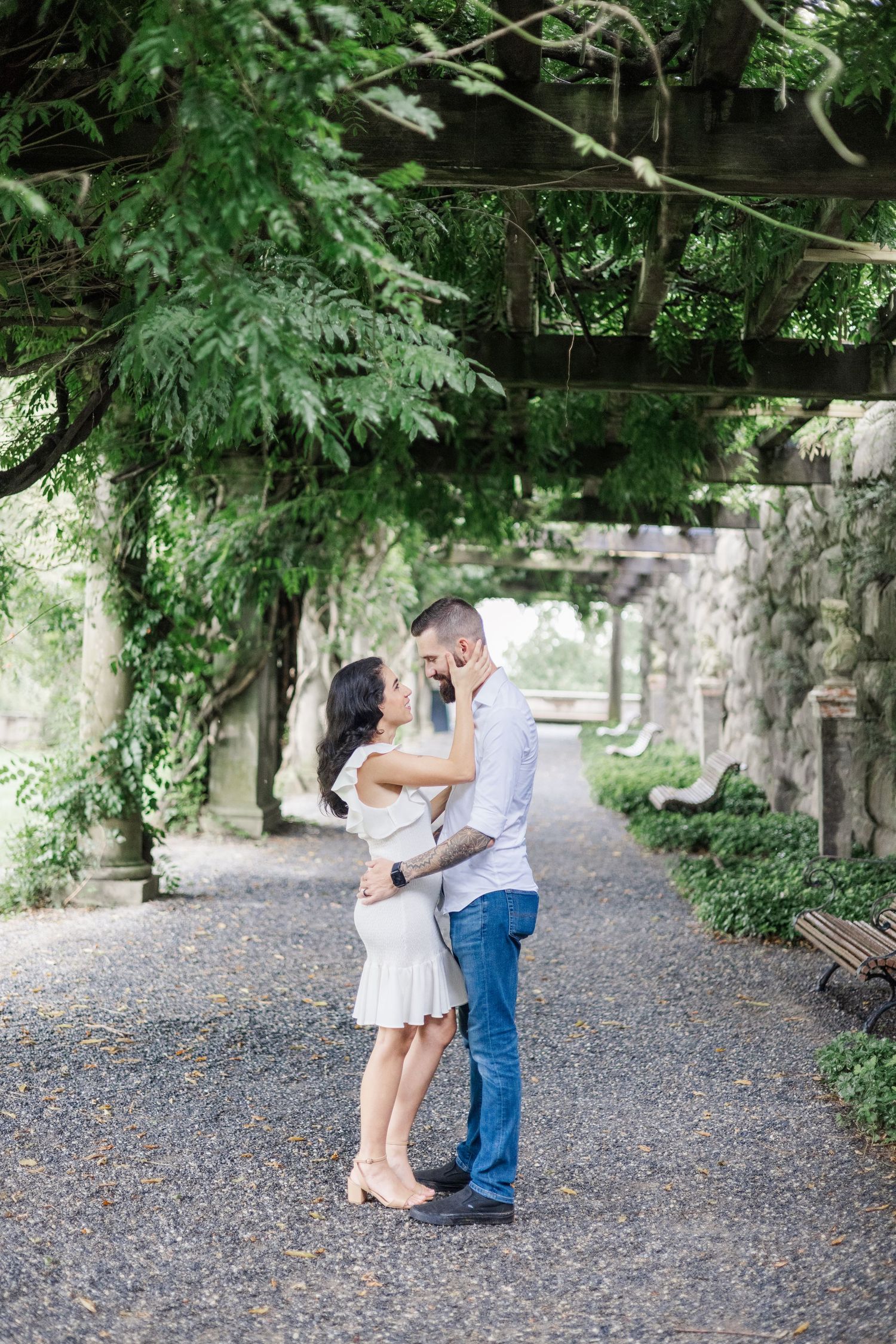 A romantic sequence unfolds on a gravel path beneath towering trees and hanging vines.