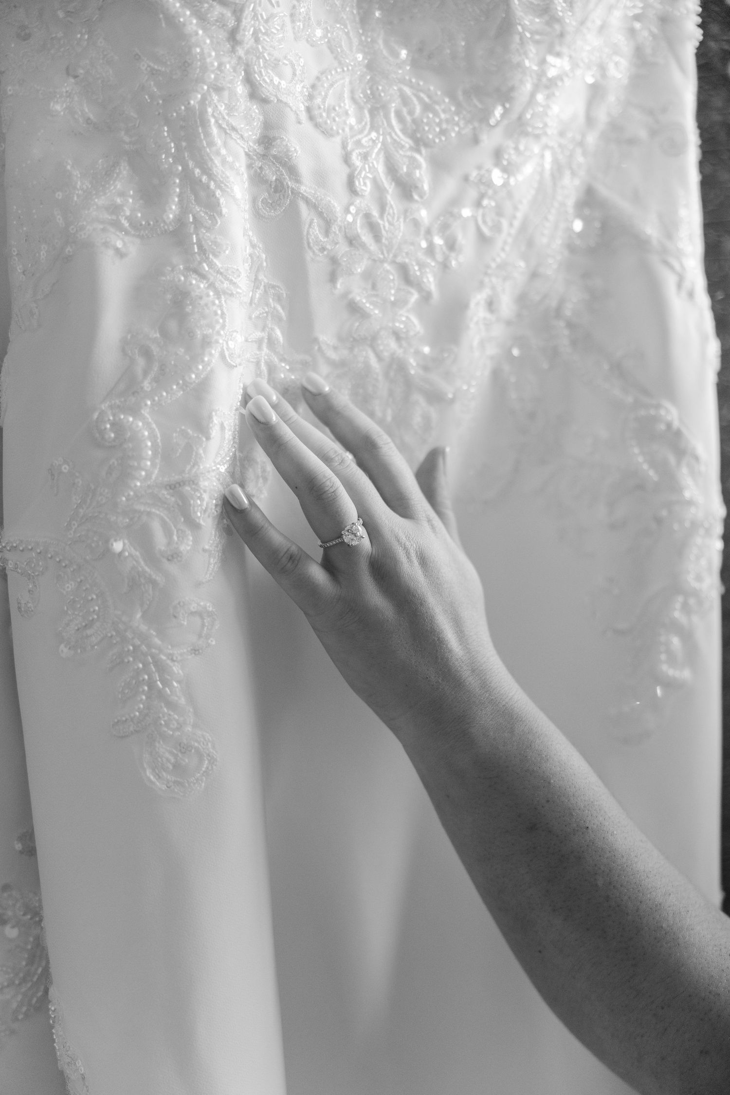 Close-up sequence showing hands gently touching delicate white lace fabric details on a wedding dress.