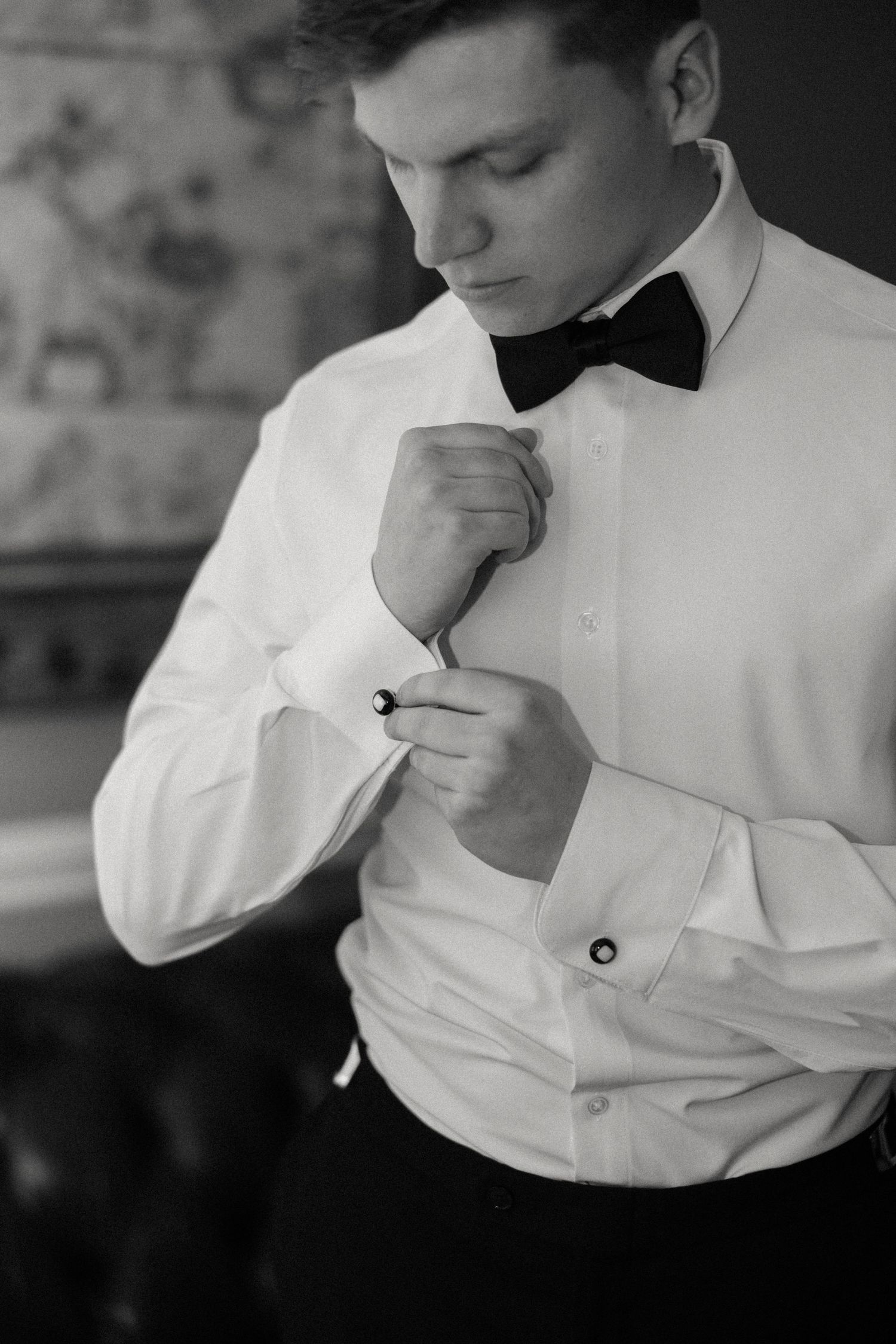 Black and white close-up sequence showing details of adjusting a formal bow tie and shirt.