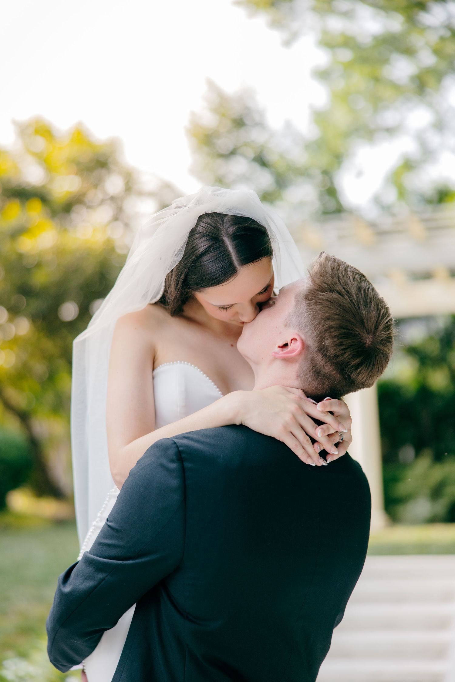 A romantic moment captured as newlyweds embrace in an outdoor garden setting.