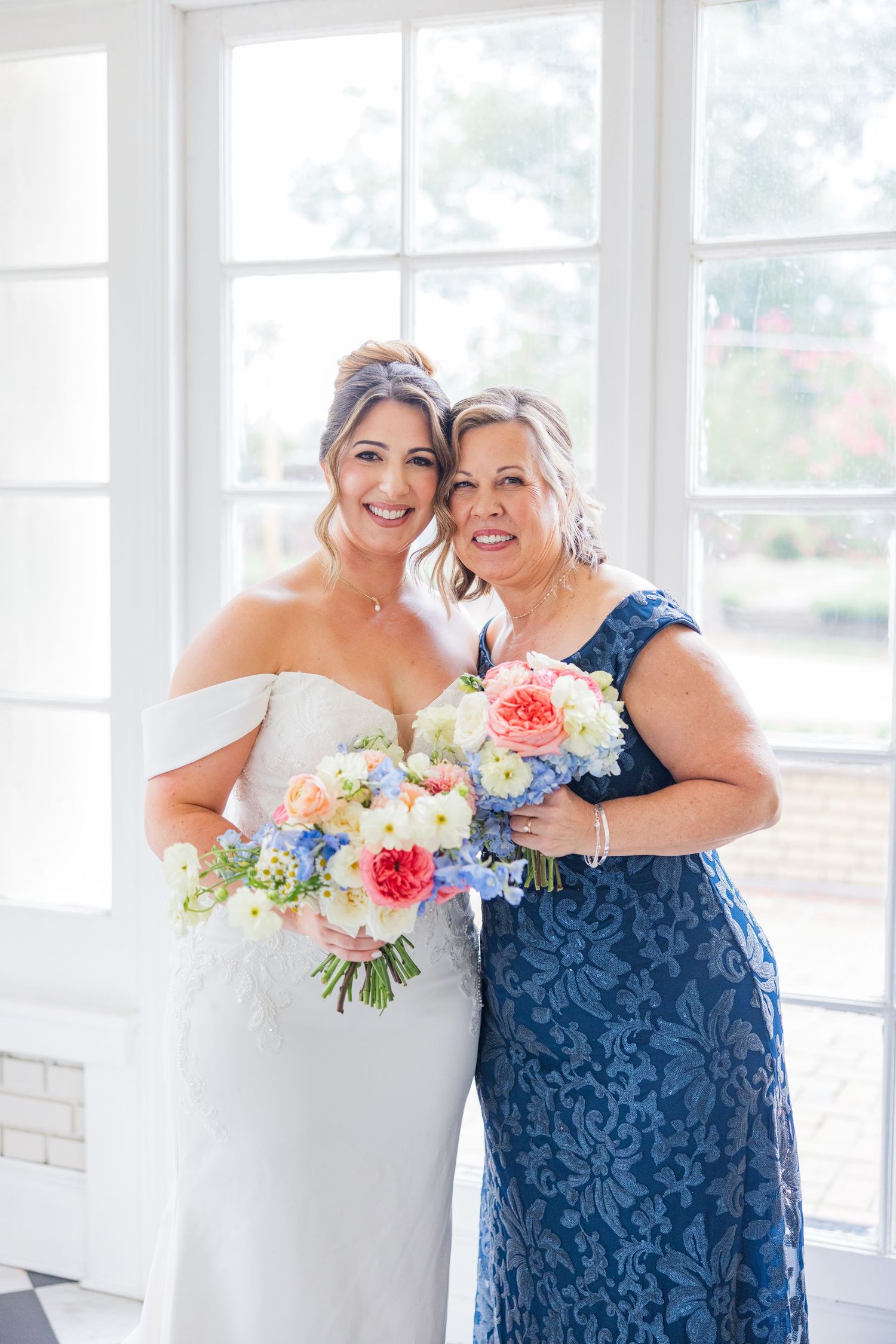 Wedding party members sharing emotional moments while holding vibrant floral bouquets.