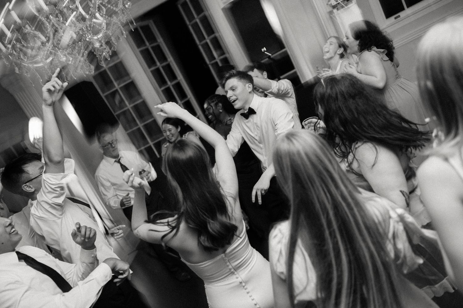 Black and white photo of wedding reception dance floor with guests celebrating.