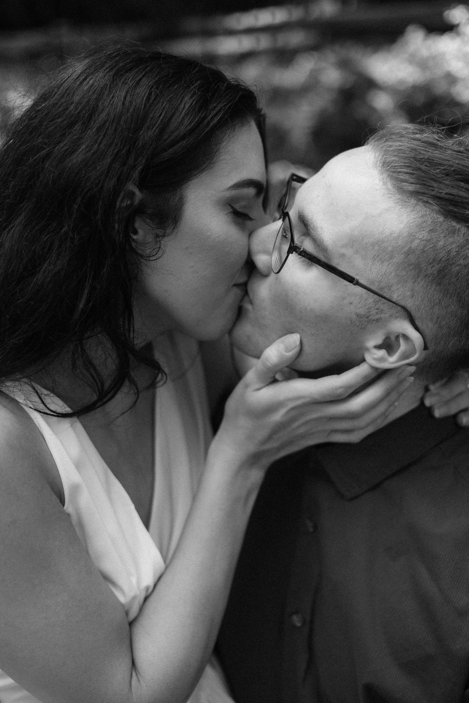 A series of romantic black and white photos showing a couple sharing intimate kisses in natural lighting.