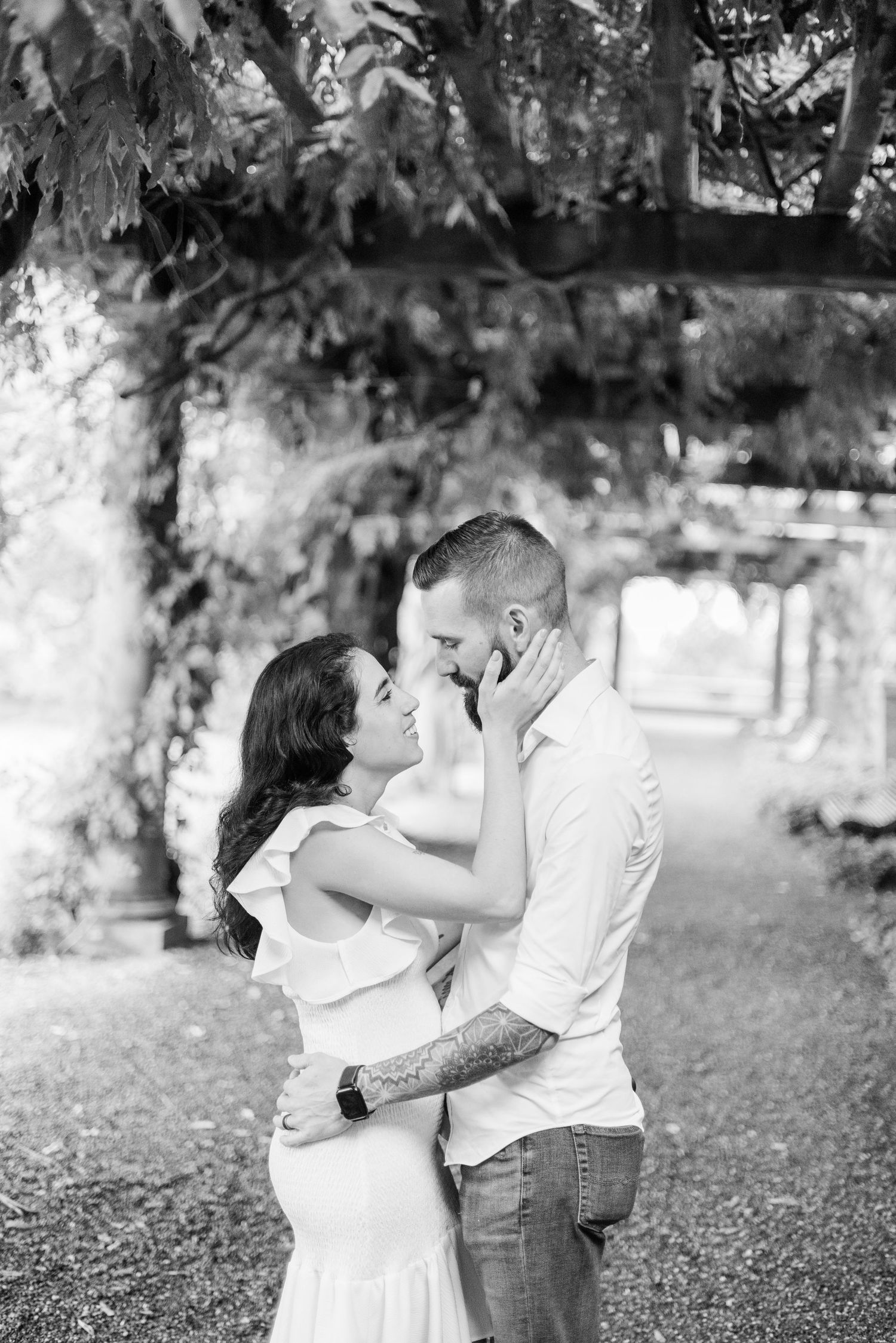 A romantic couple shares intimate moments in a series of black and white photographs taken outdoors under trees.