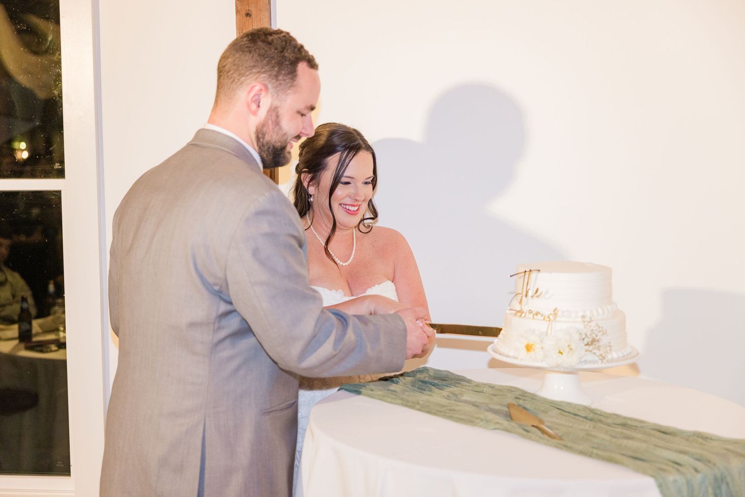 Wedding couple enjoying cake cutting moment at reception.