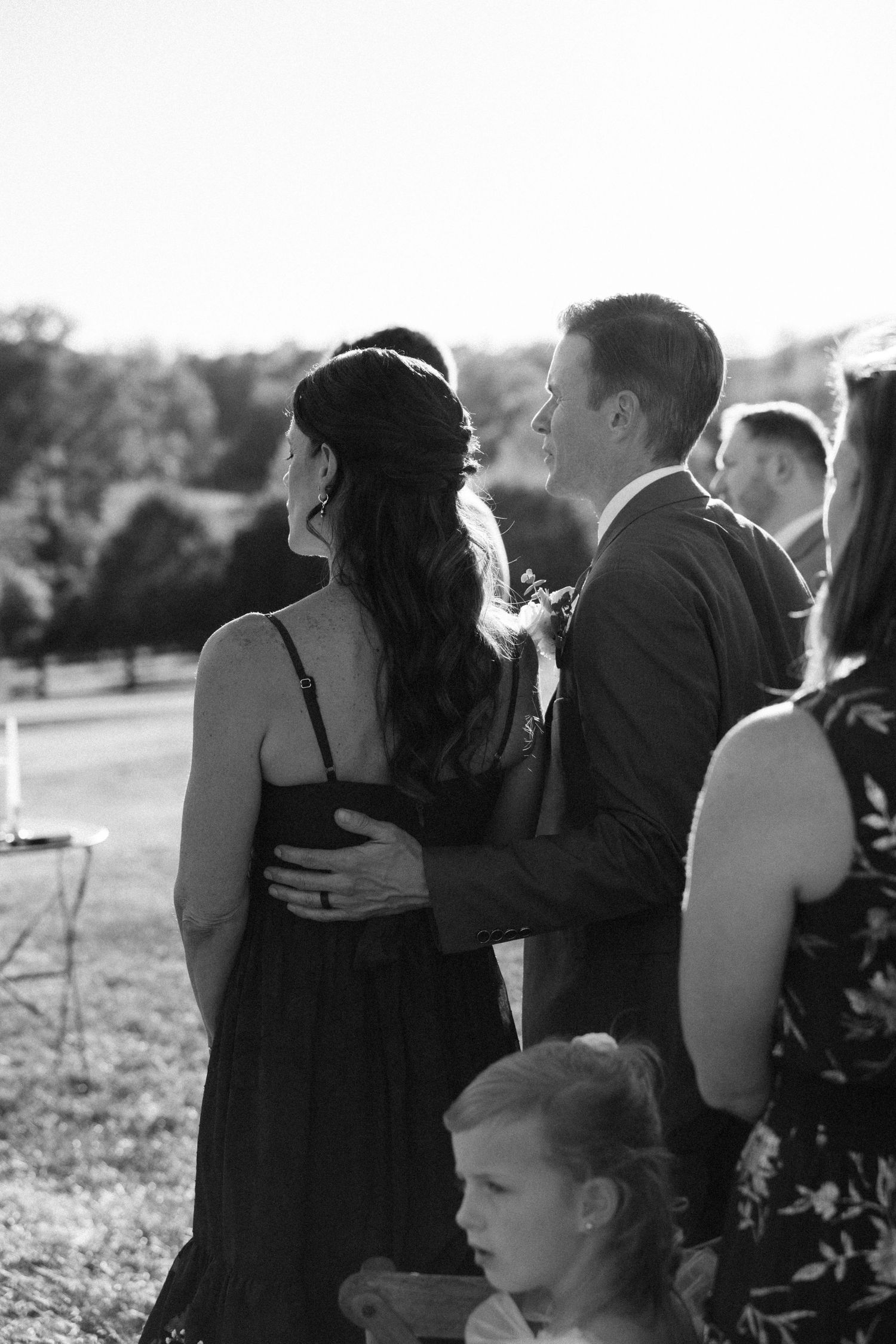 Wedding guests embrace and share emotional moments during an outdoor celebration.