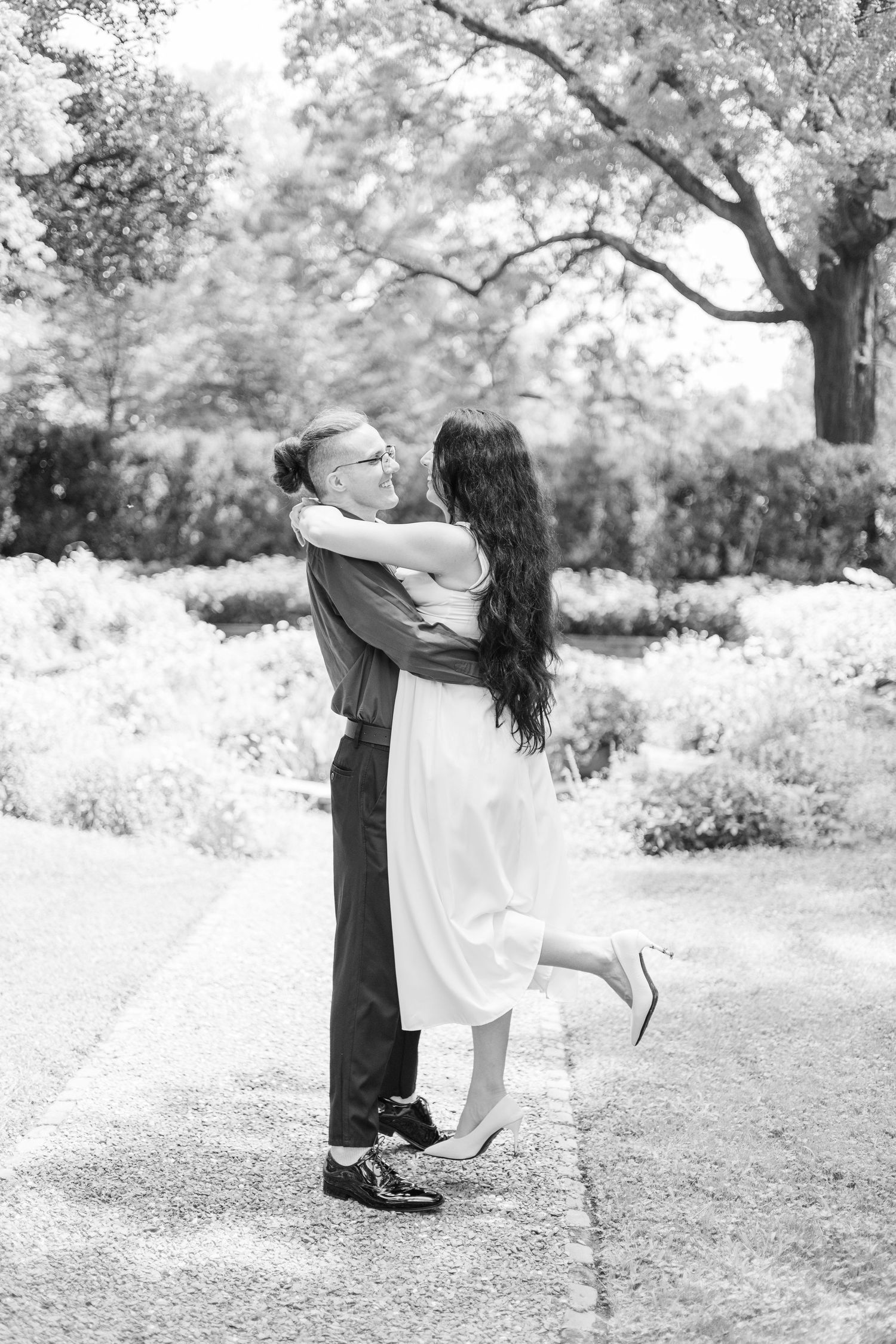 A black and white series captures romantic moments between a couple in an outdoor garden setting.