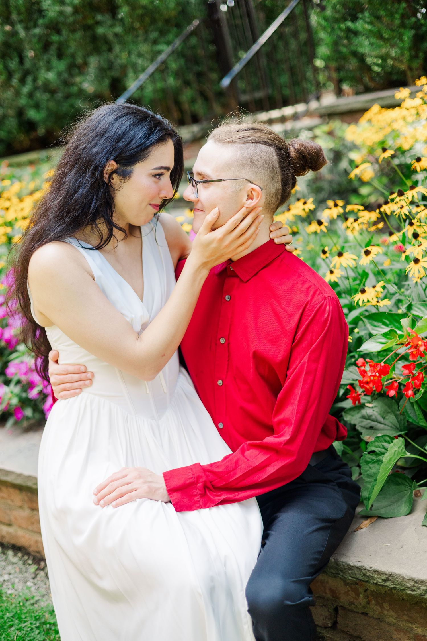A tender moment captured between a couple sitting among colorful flowers in a garden.