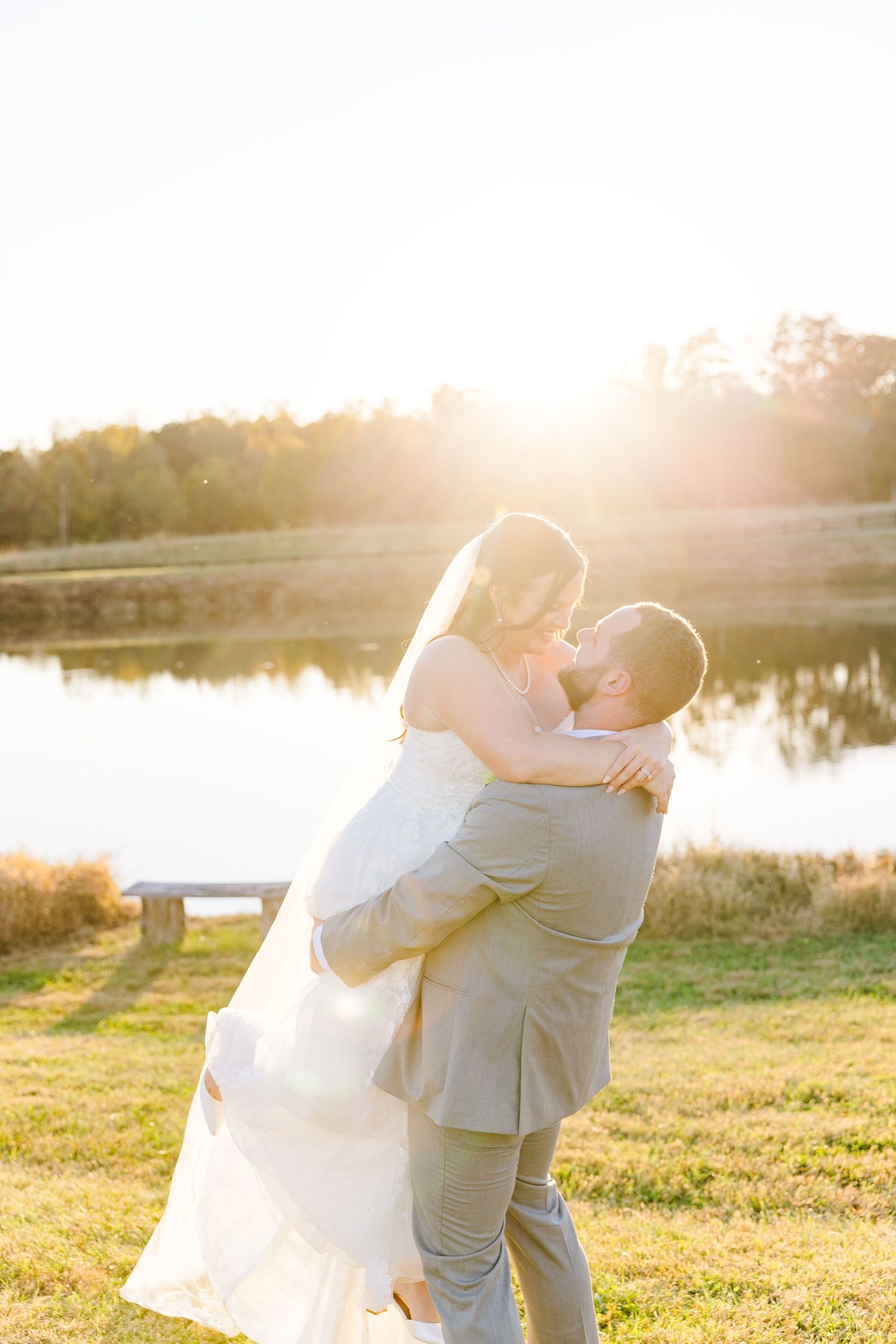 A couple shares romantic sunset kisses by a lake during their wedding photo session.