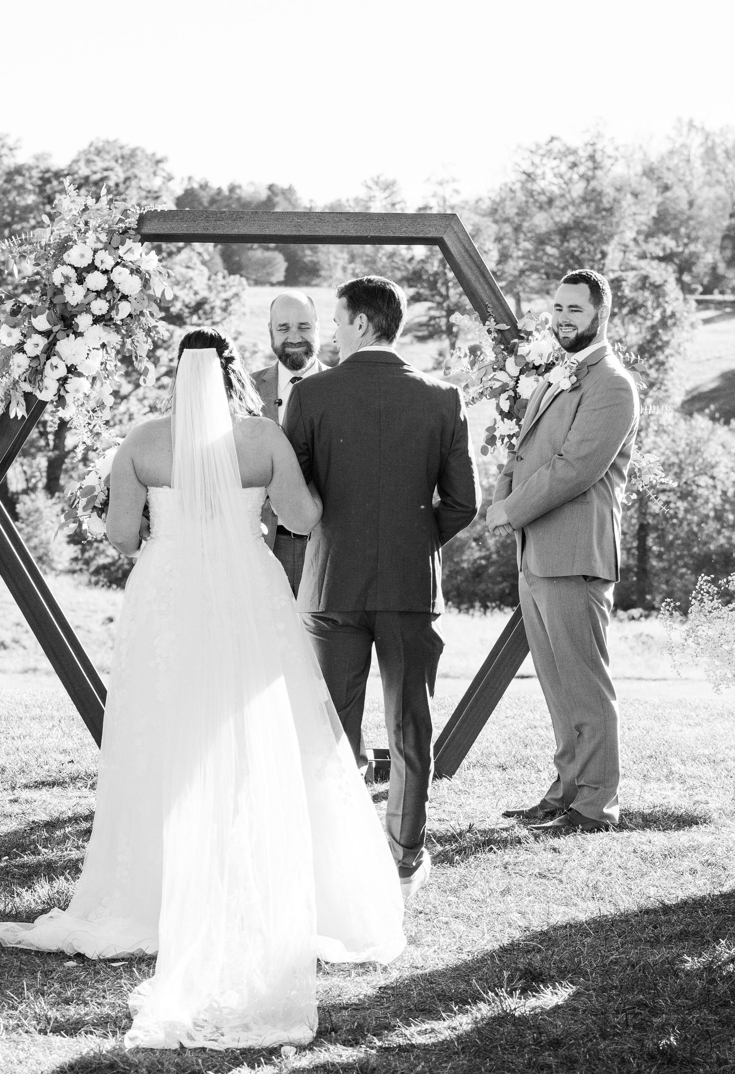 Wedding ceremony setup with wooden hexagon arch frame outdoors.
