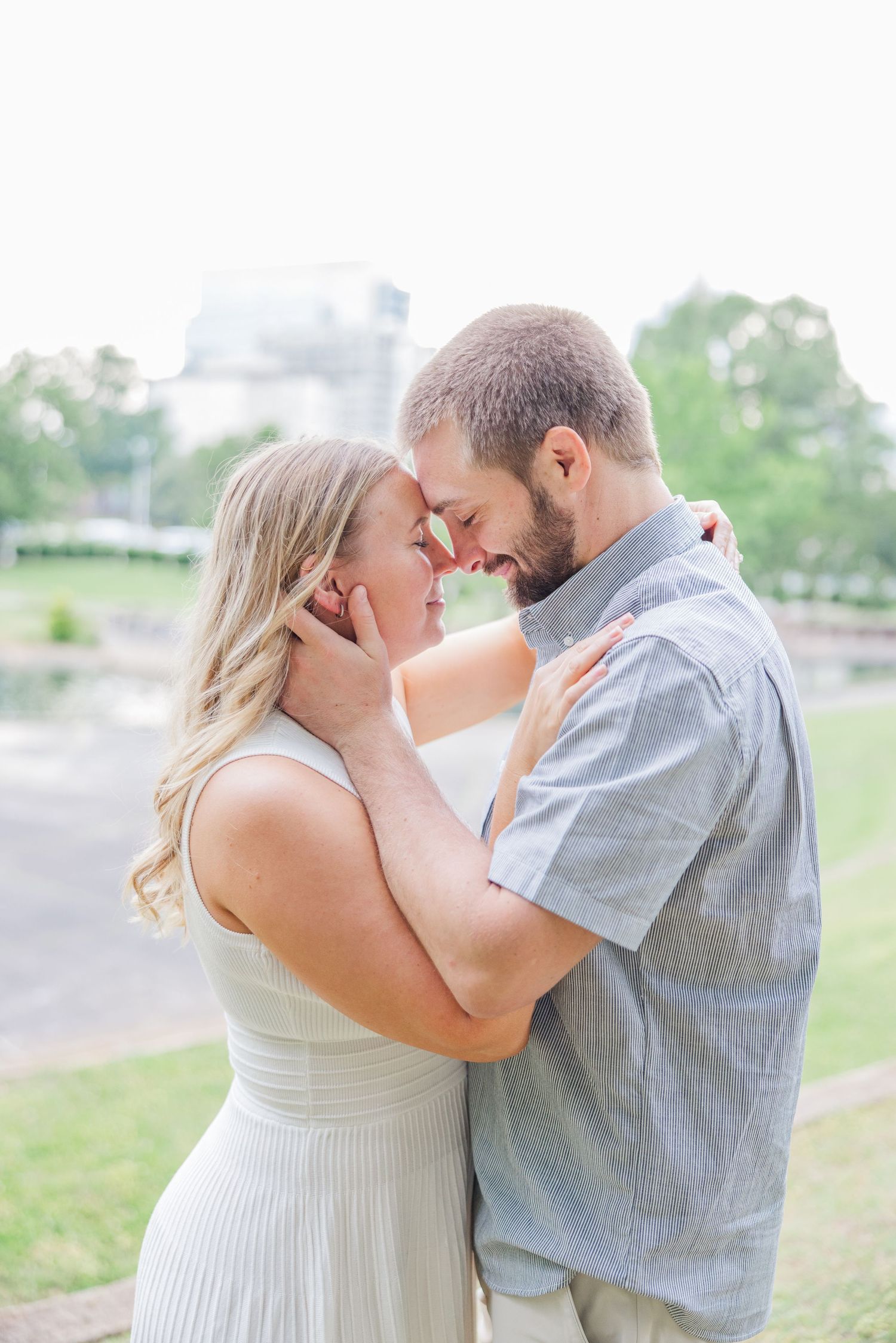 A romantic couple shares intimate moments in a series of outdoor engagement photos in a park setting.