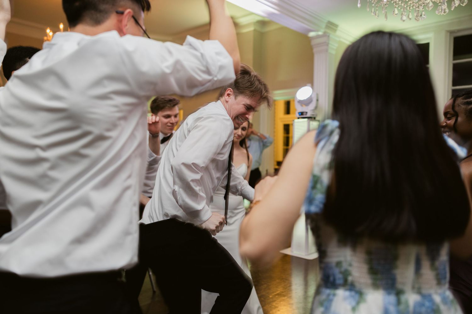 Energetic wedding reception scene with guests dancing and celebrating.